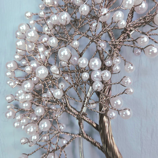 Decorative tree made of branches and pearls on a light blue background
