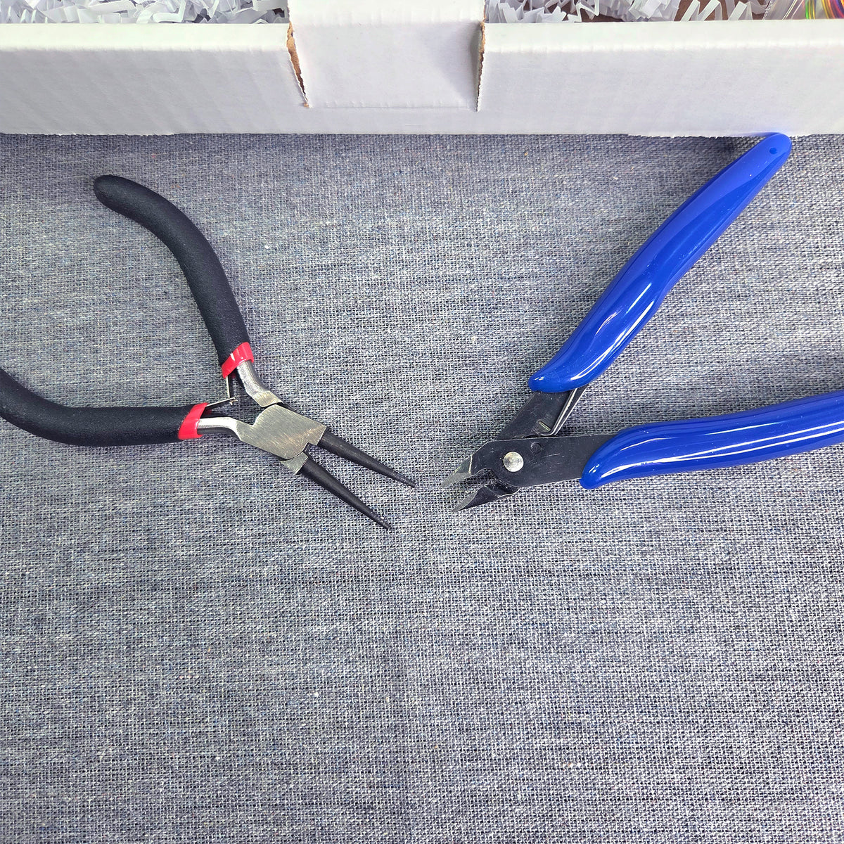 Pair of black and red pliers and a blue and black tool on a gray fabric background