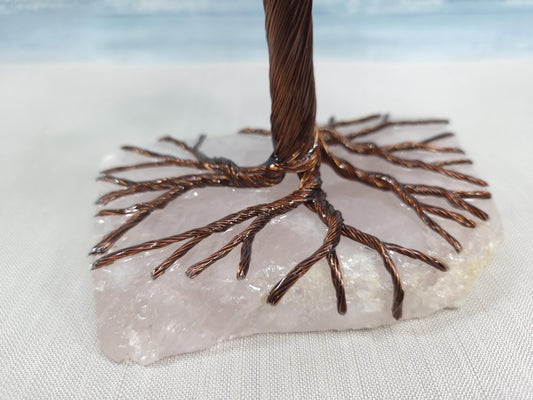 Decorative tree sculpture on a stone base with a light blue gradient background
