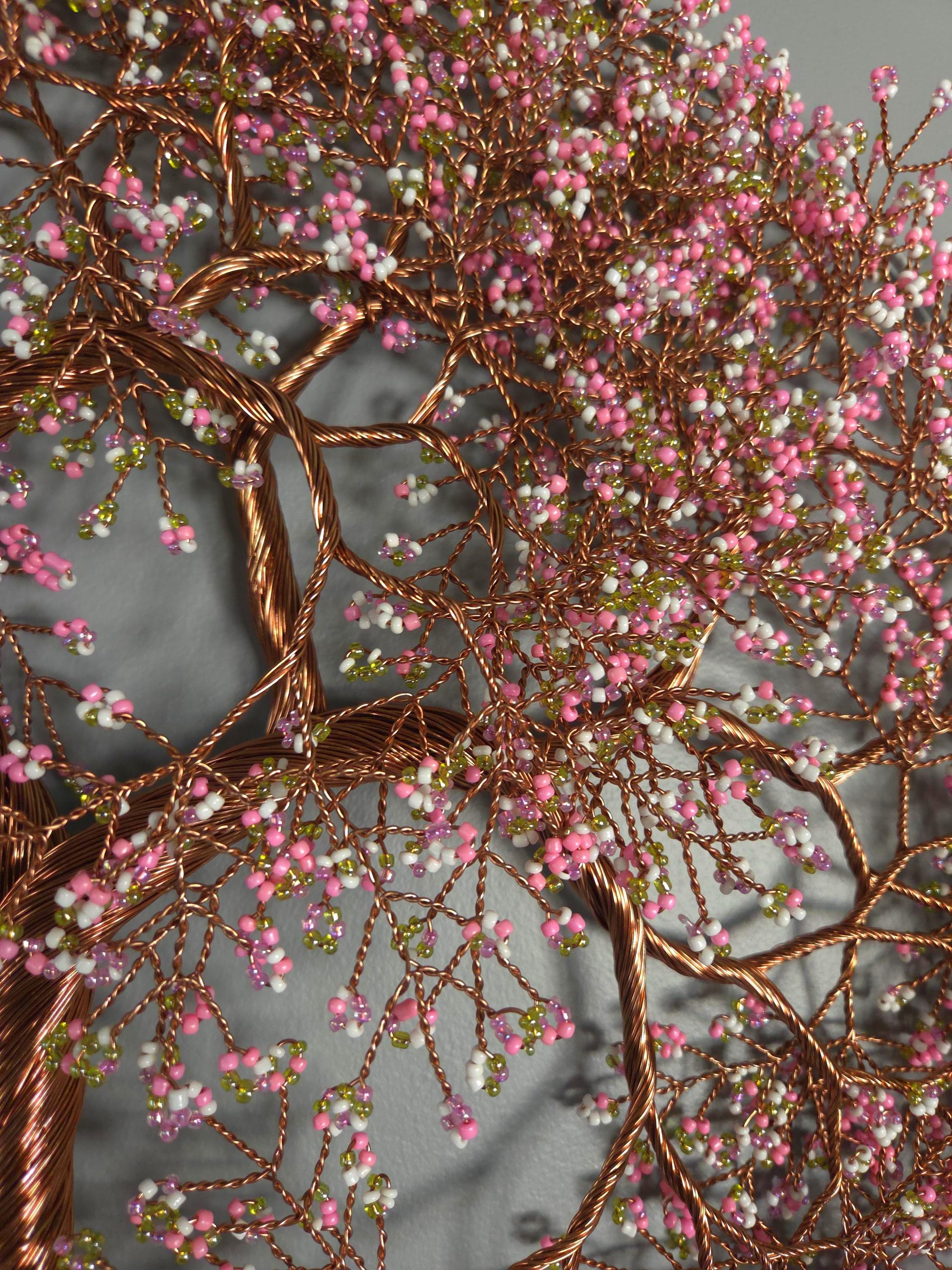 Decorative tree sculpture with pink and green beads on a gray background