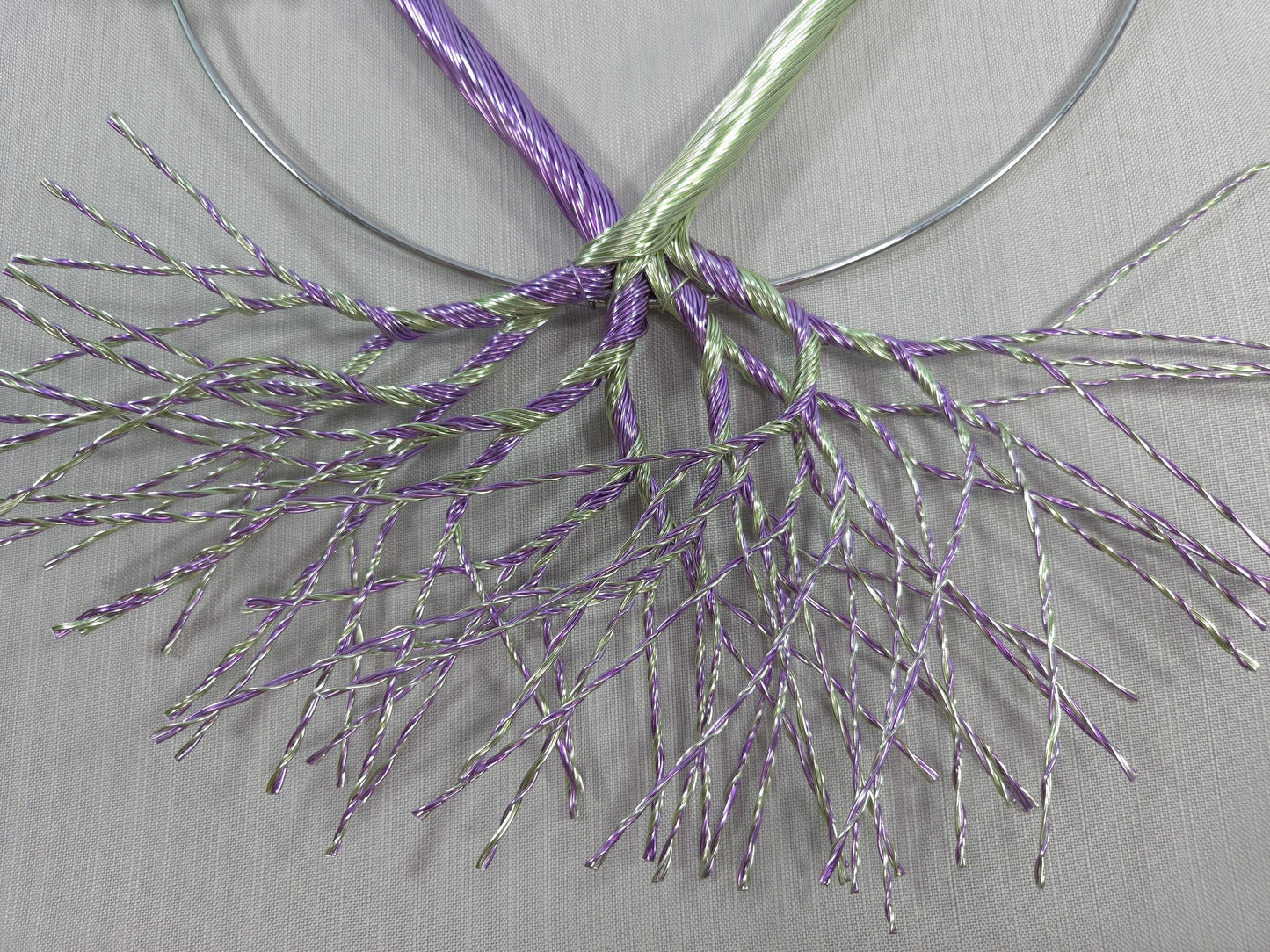 Decorative wreath with purple and green branches on a plain background