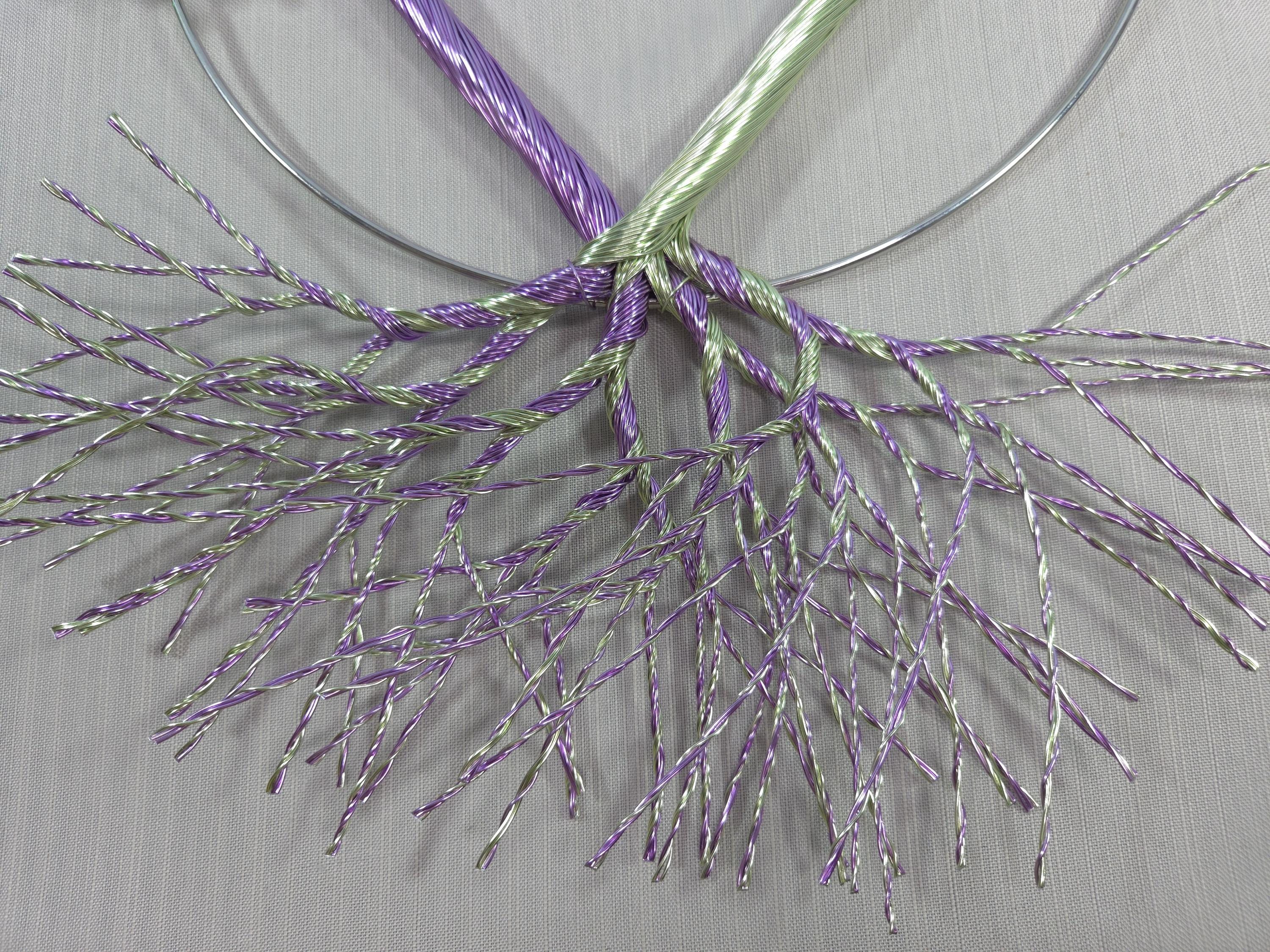 Decorative wreath with purple and green branches on a plain background