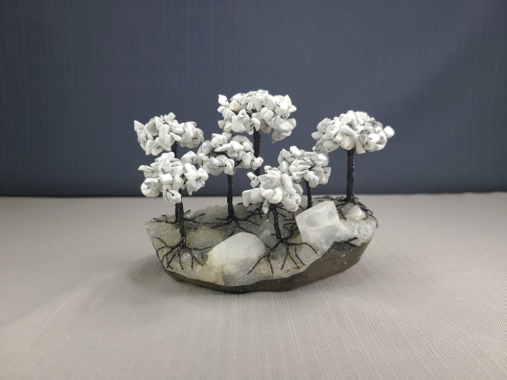 Decorative stone sculpture with white branches on a gray surface and dark background