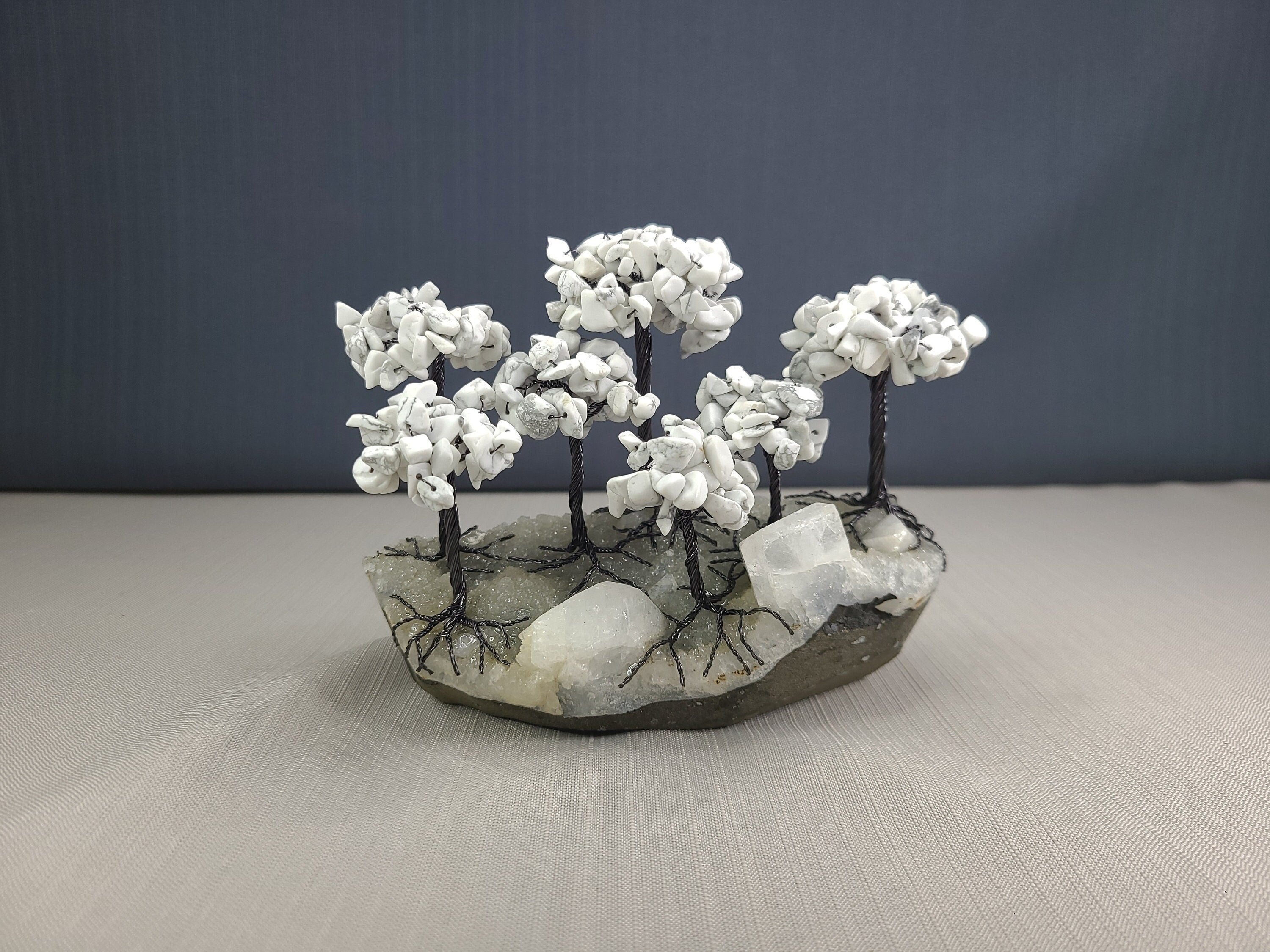 Decorative stone sculpture with white branches on a gray surface and dark background