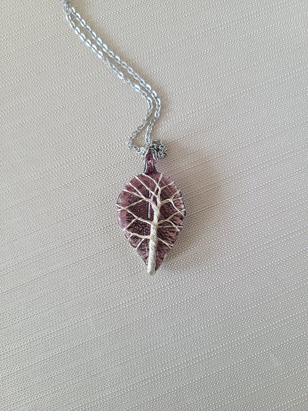 Purple leaf-shaped pendant on a silver chain against a light gray background