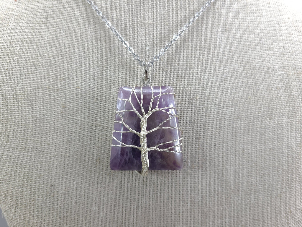 Necklace with a purple pendant featuring a silver tree design on a gray background