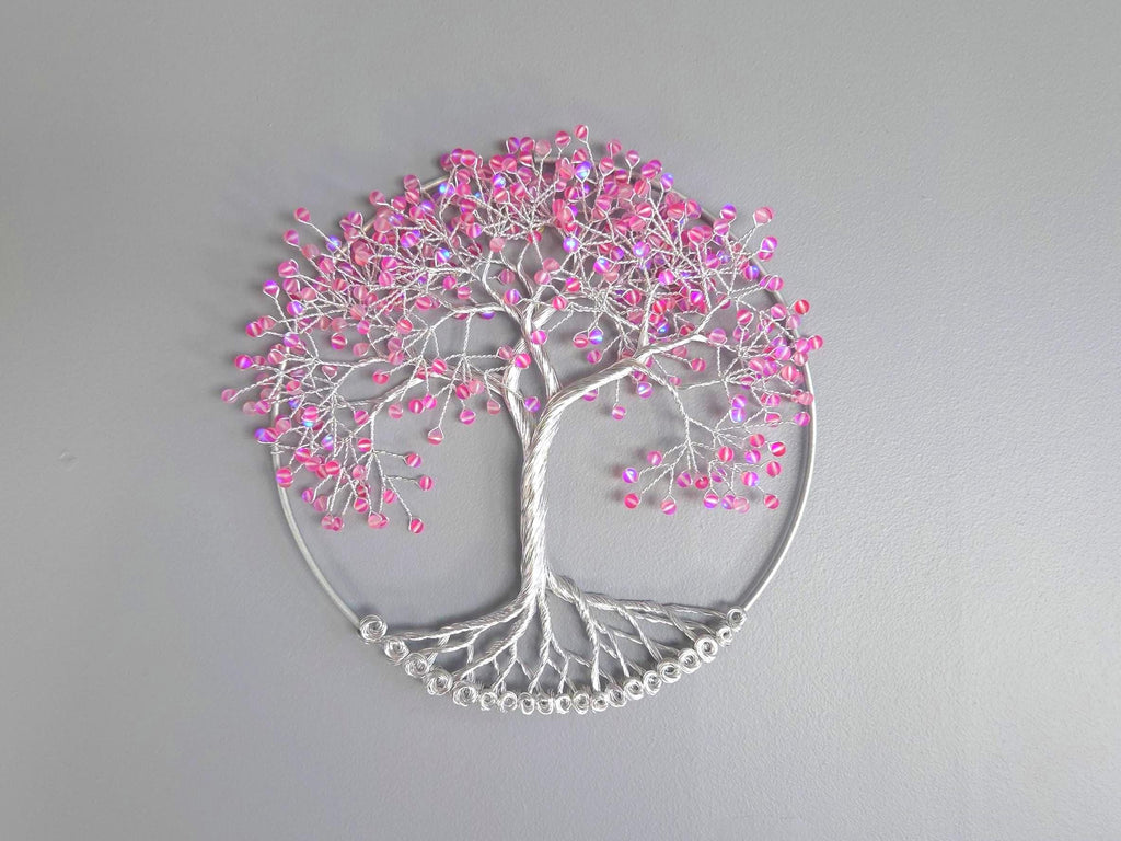 Decorative wall art of a tree with pink beads on a gray background
