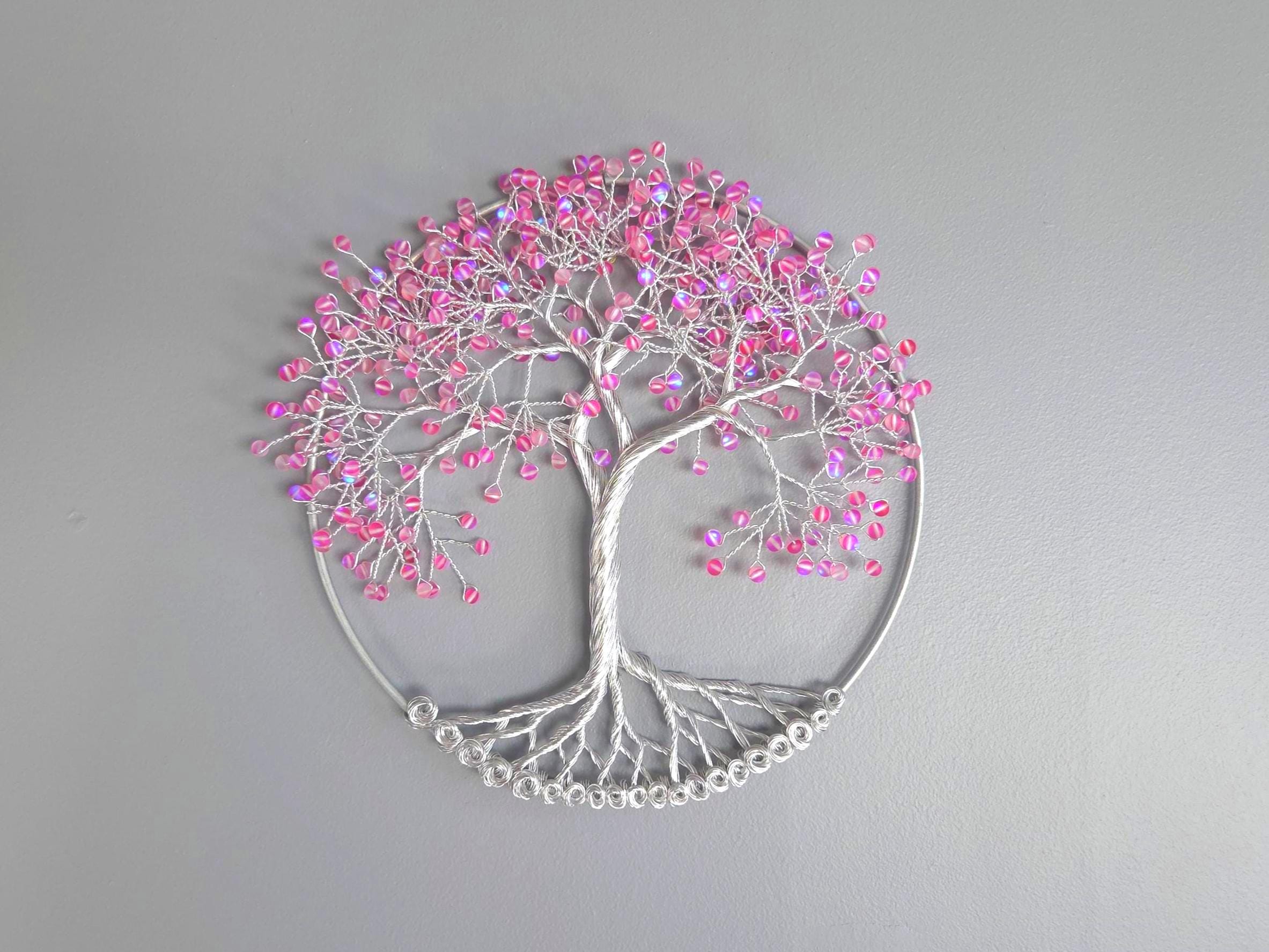 Decorative wall art of a tree with pink beads on a gray background