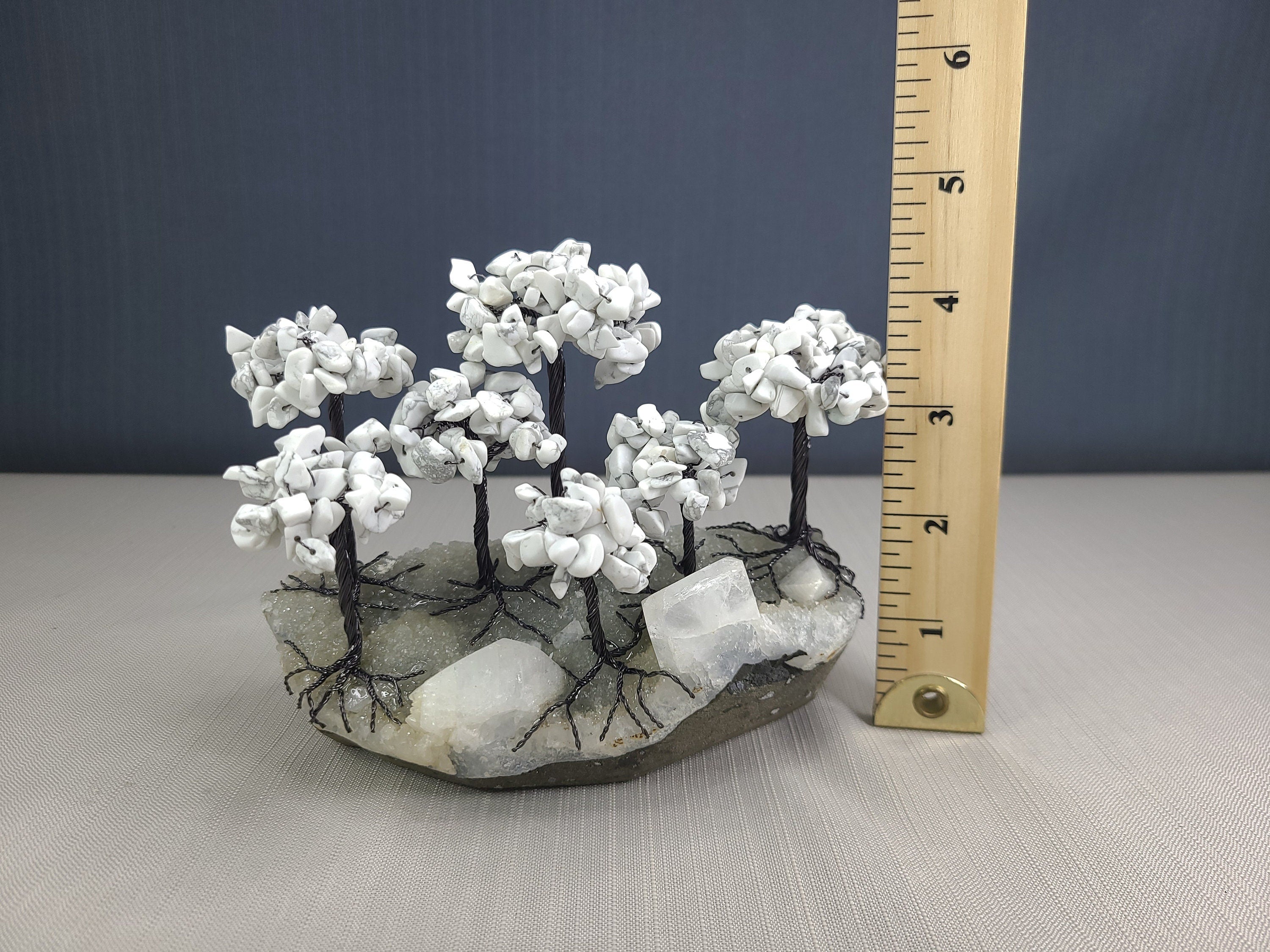 Decorative stone sculpture with white branches next to a ruler on a gray surface