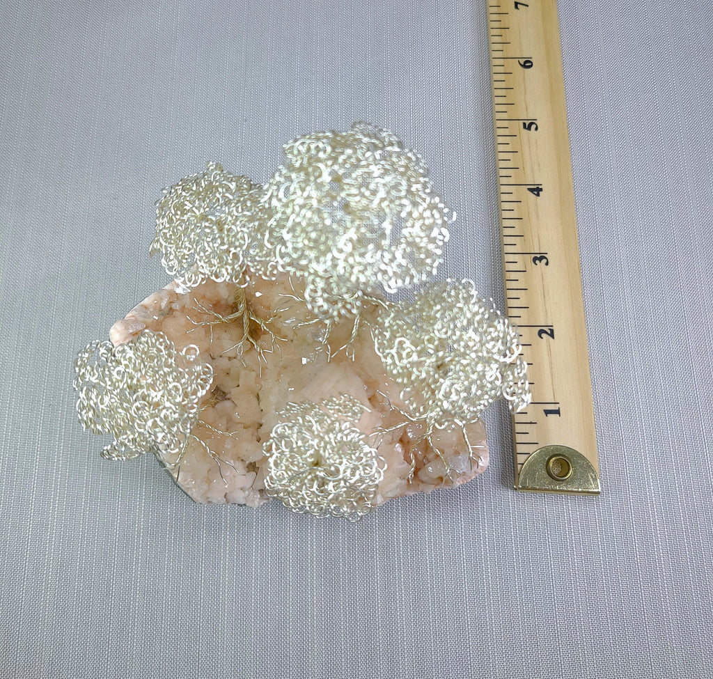 Decorative wire mesh on a stone base with a ruler for scale on a gray background