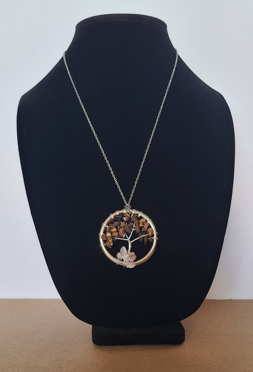 Necklace with a tree of life pendant on a black bust against a white background