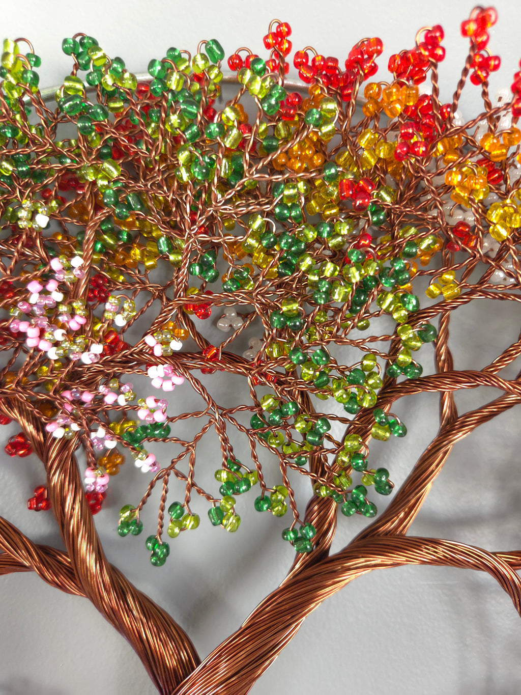 Decorative tree sculpture with multicolored beads on a gray background