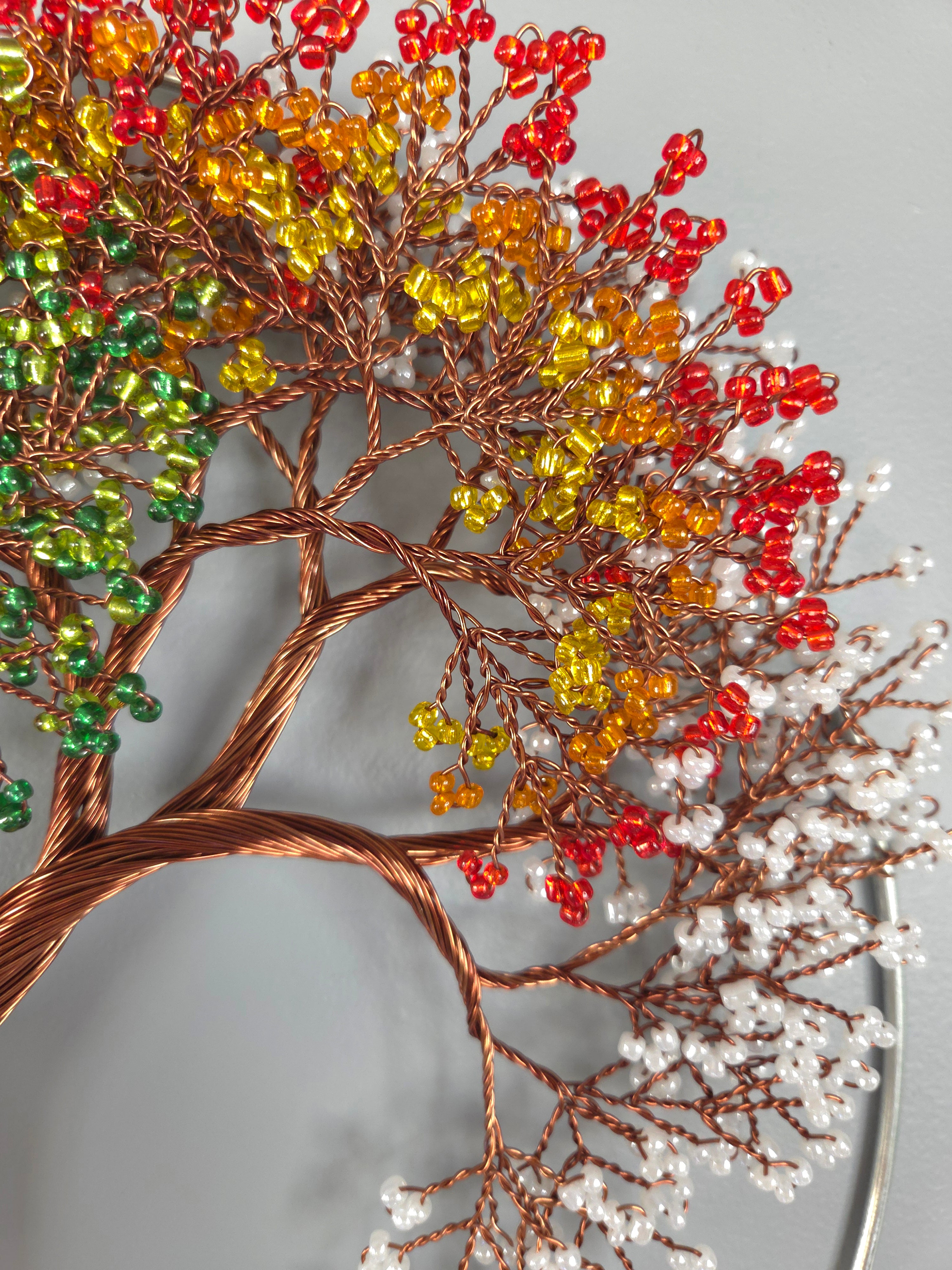 Decorative wall art of a tree with colorful beads on a gray background