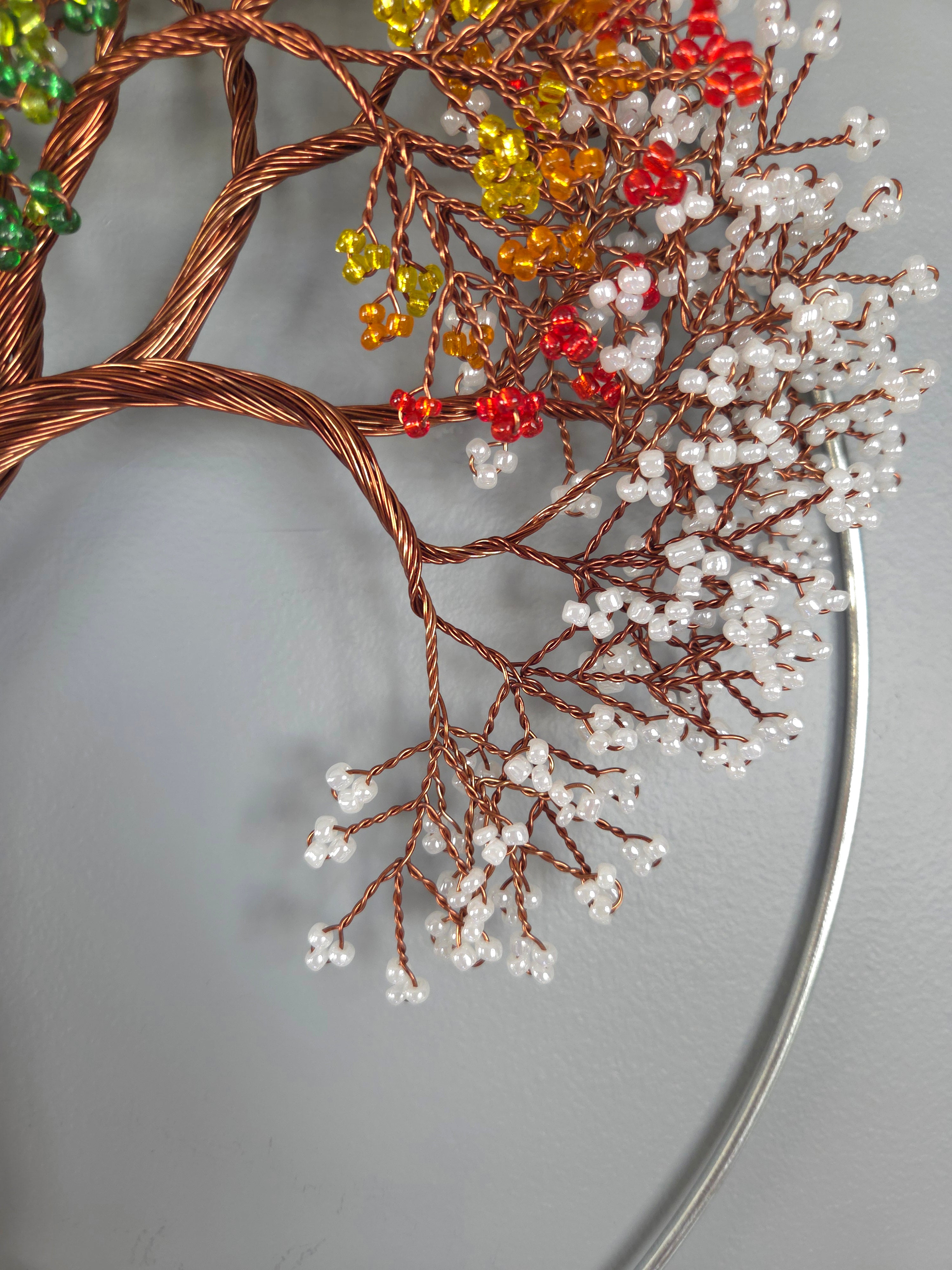 Decorative wreath with copper branches and colorful beads on a gray background