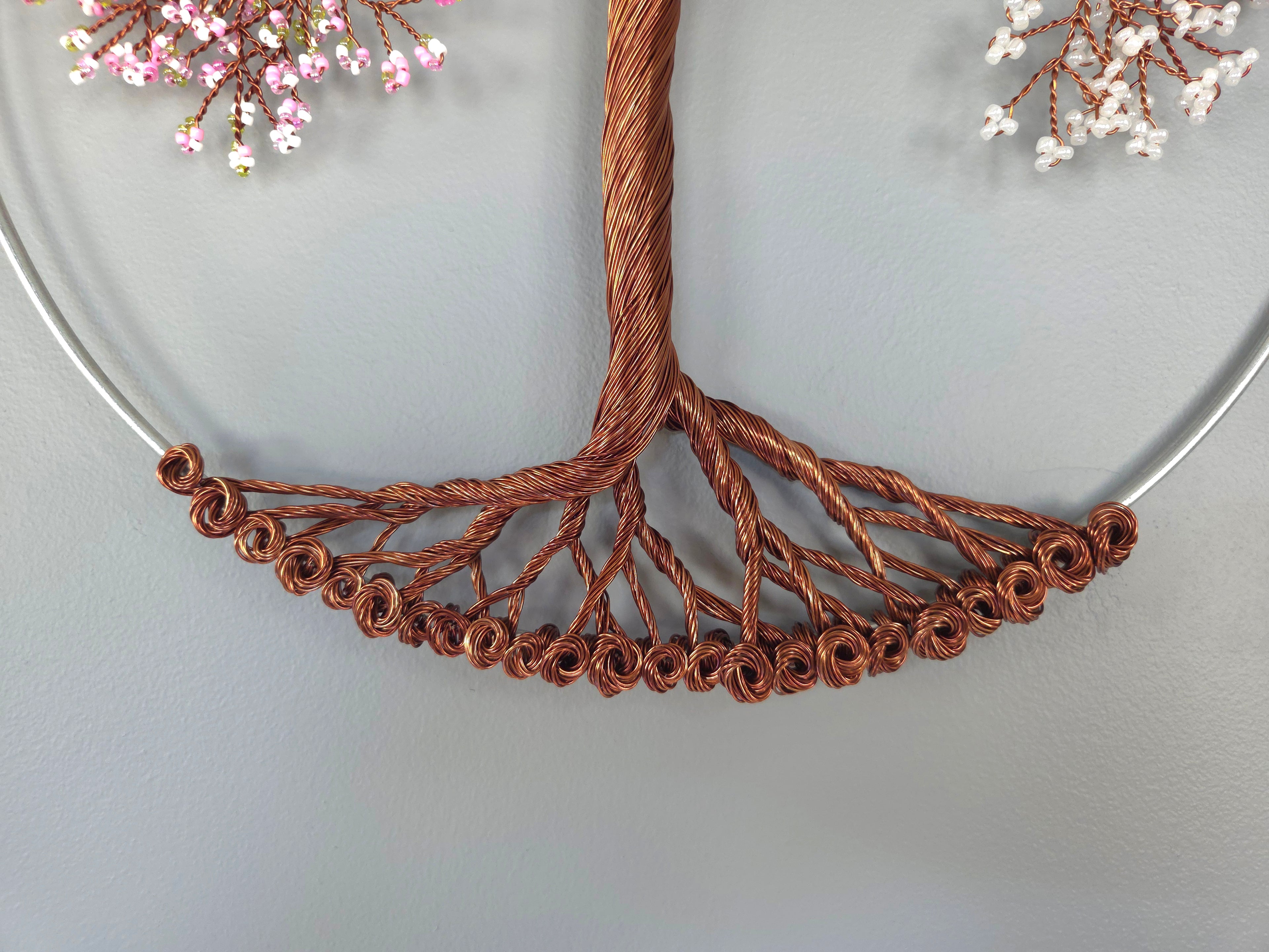 Close-up of a copper wire tree branch necklace on a light gray background