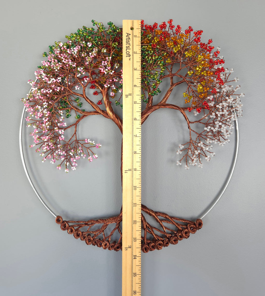 Decorative wall art of a tree with colorful leaves and a ruler for scale on a gray background
