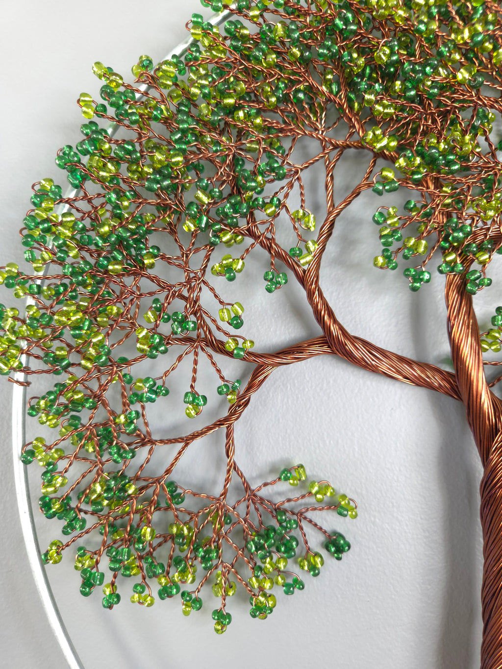 Decorative wall art of a tree with green beads on a white background