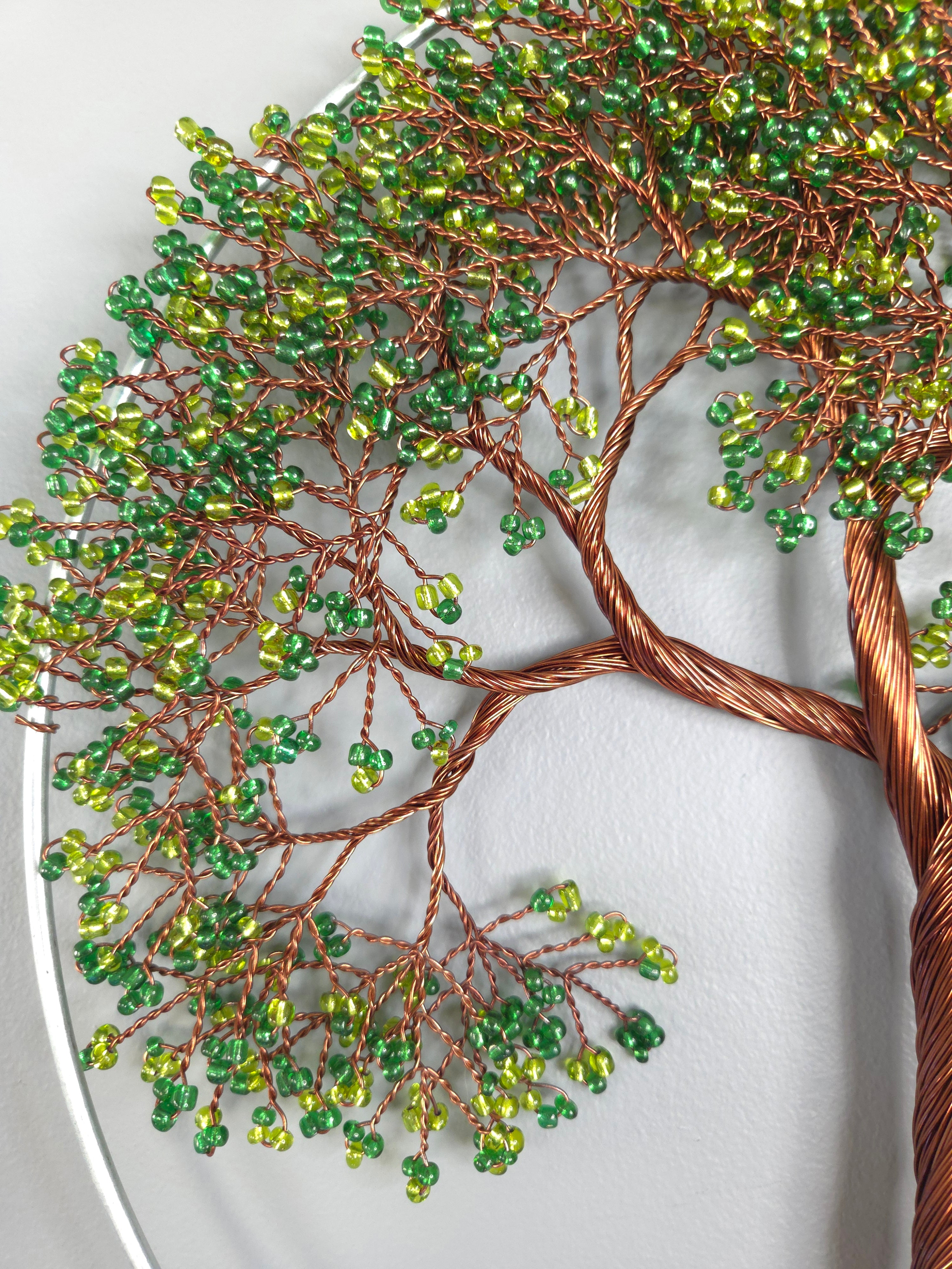 Decorative wall art of a tree with green beads on a white background