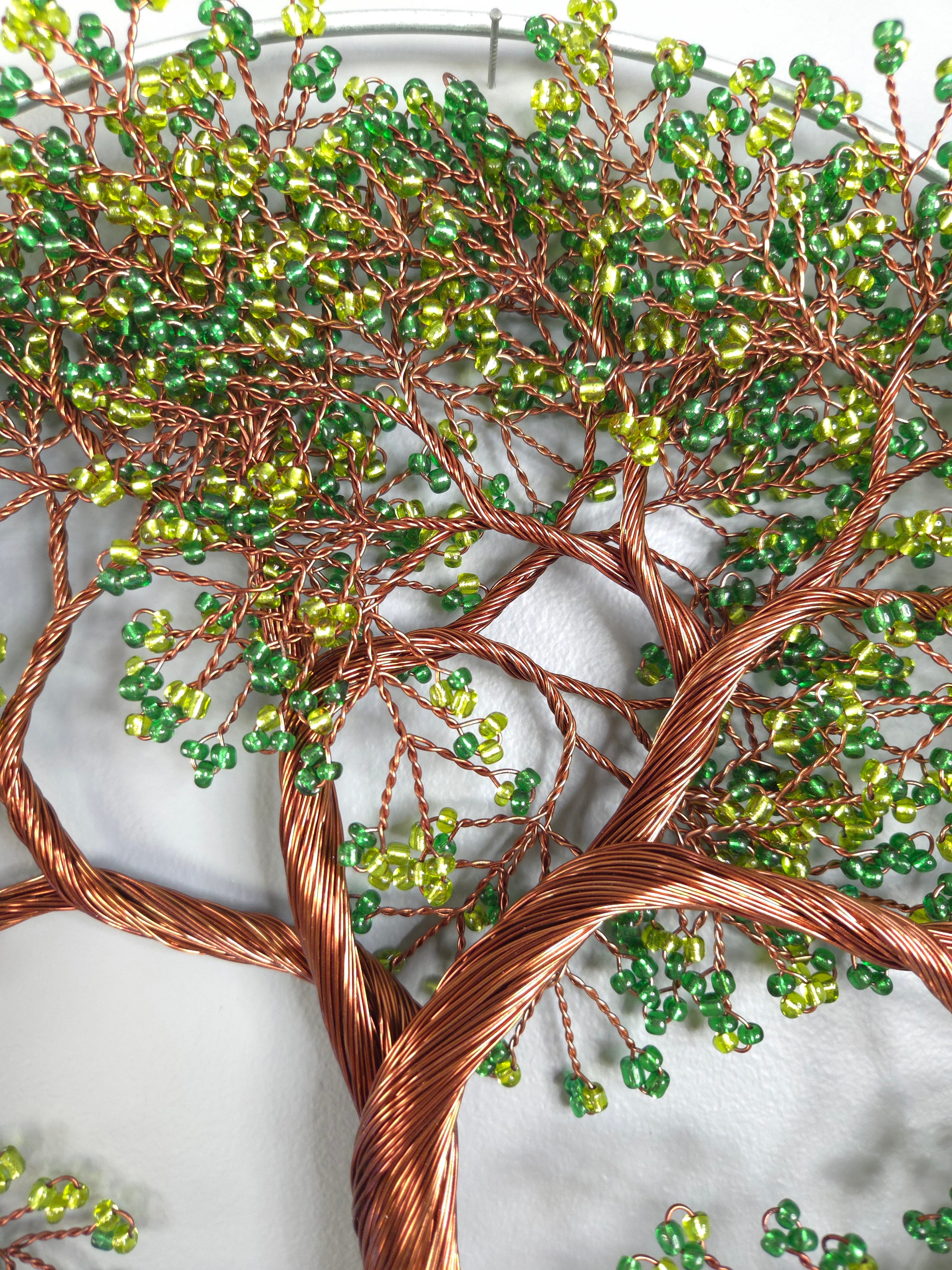 Decorative wall art of a tree made from wire and beads on a white background