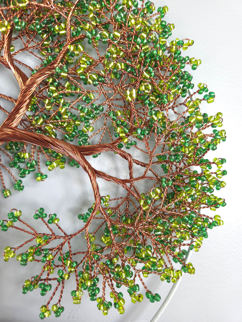 Decorative tree made of copper wire and green beads on a white background