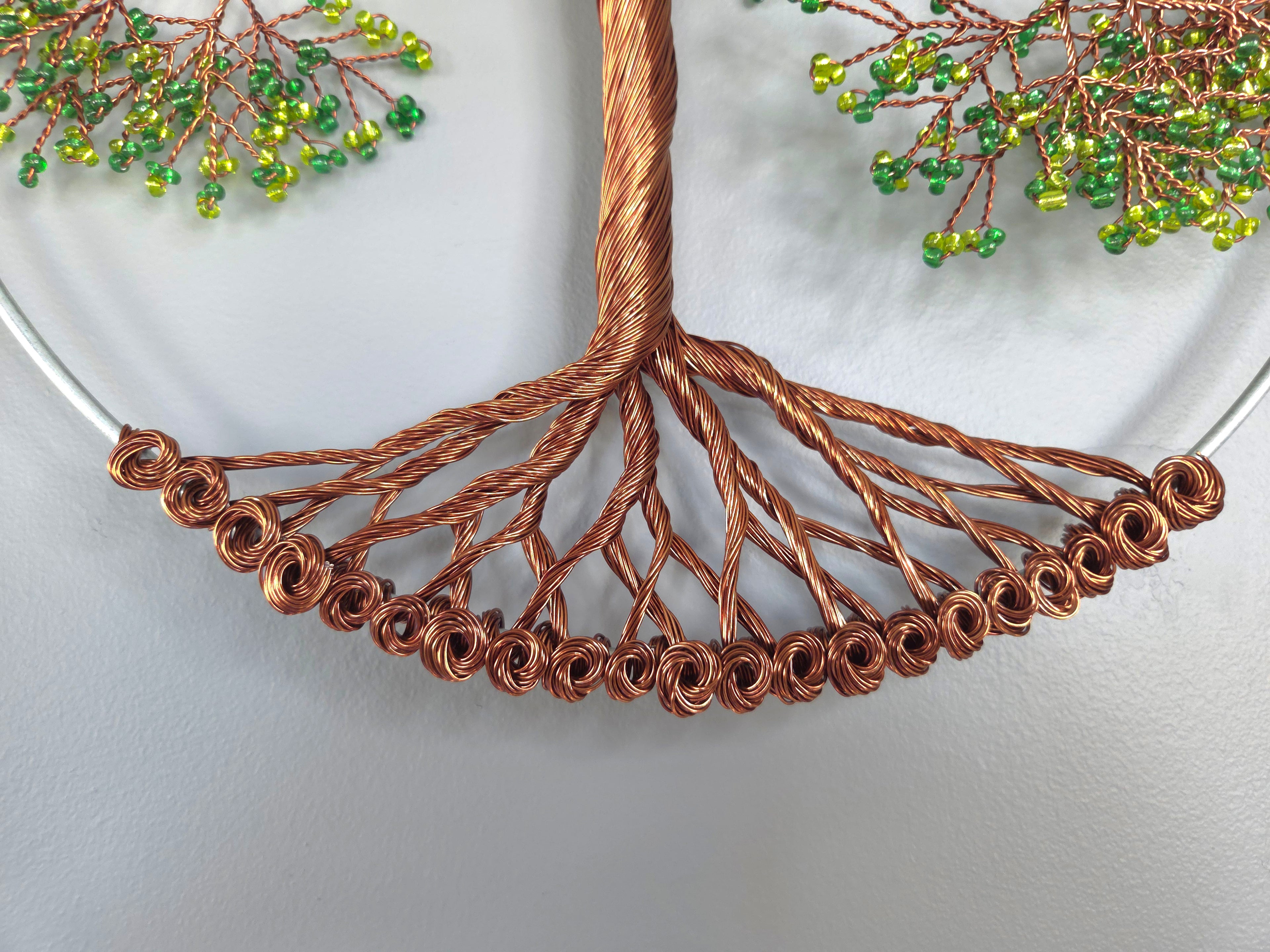 Copper wire tree with green beads on a white background