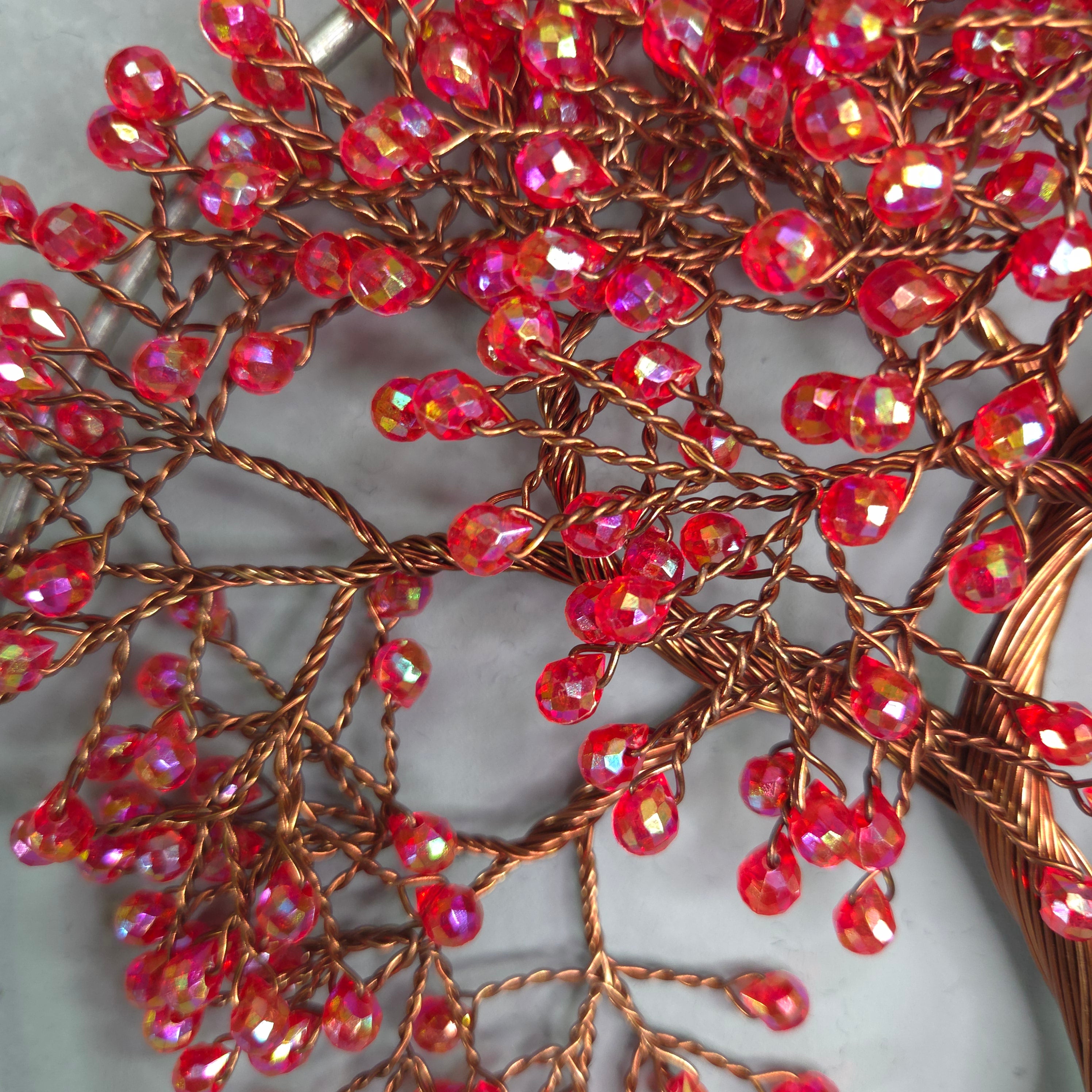 Close-up of a decorative item with red beads and copper wire on a white background