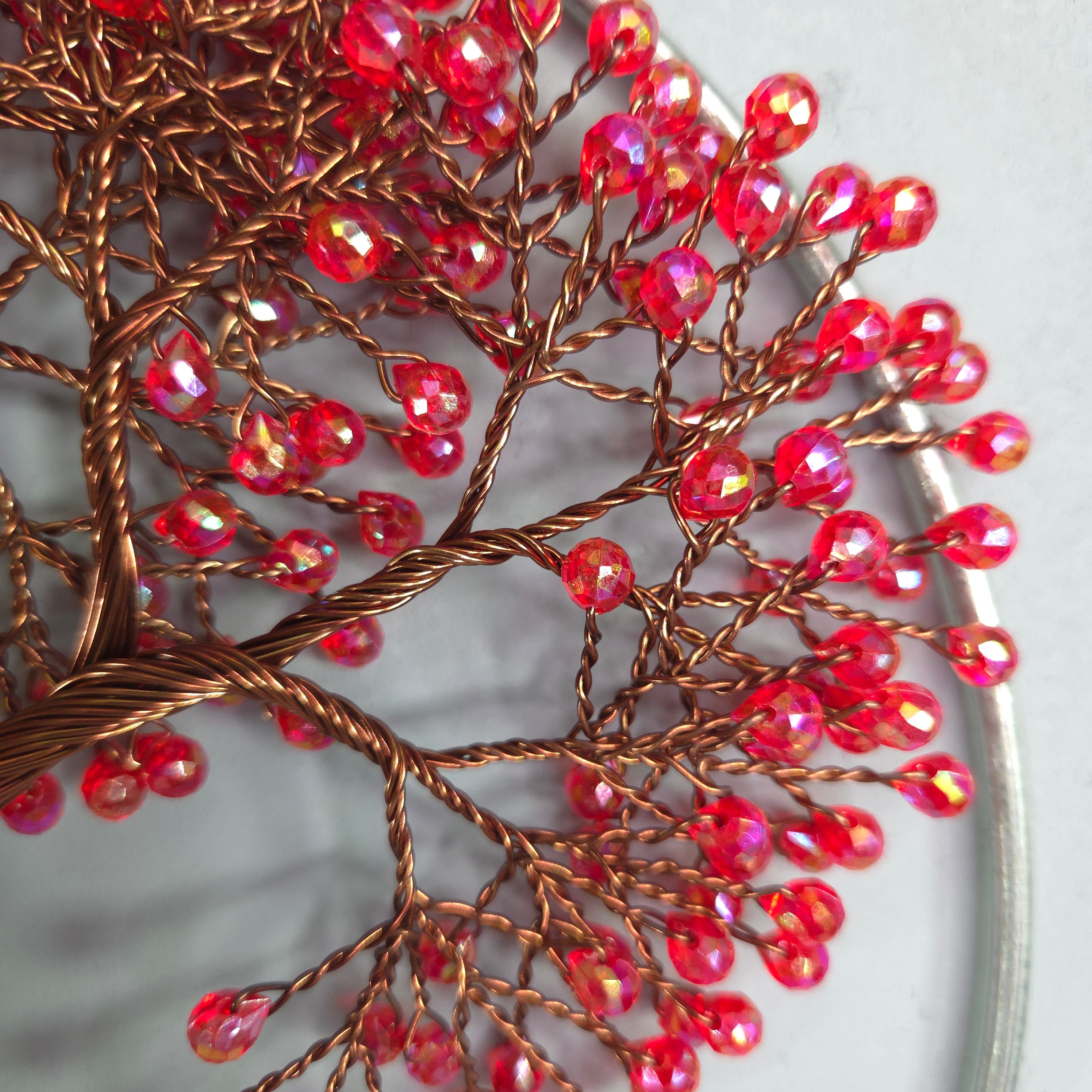 Decorative tree sculpture with red beads on a white background