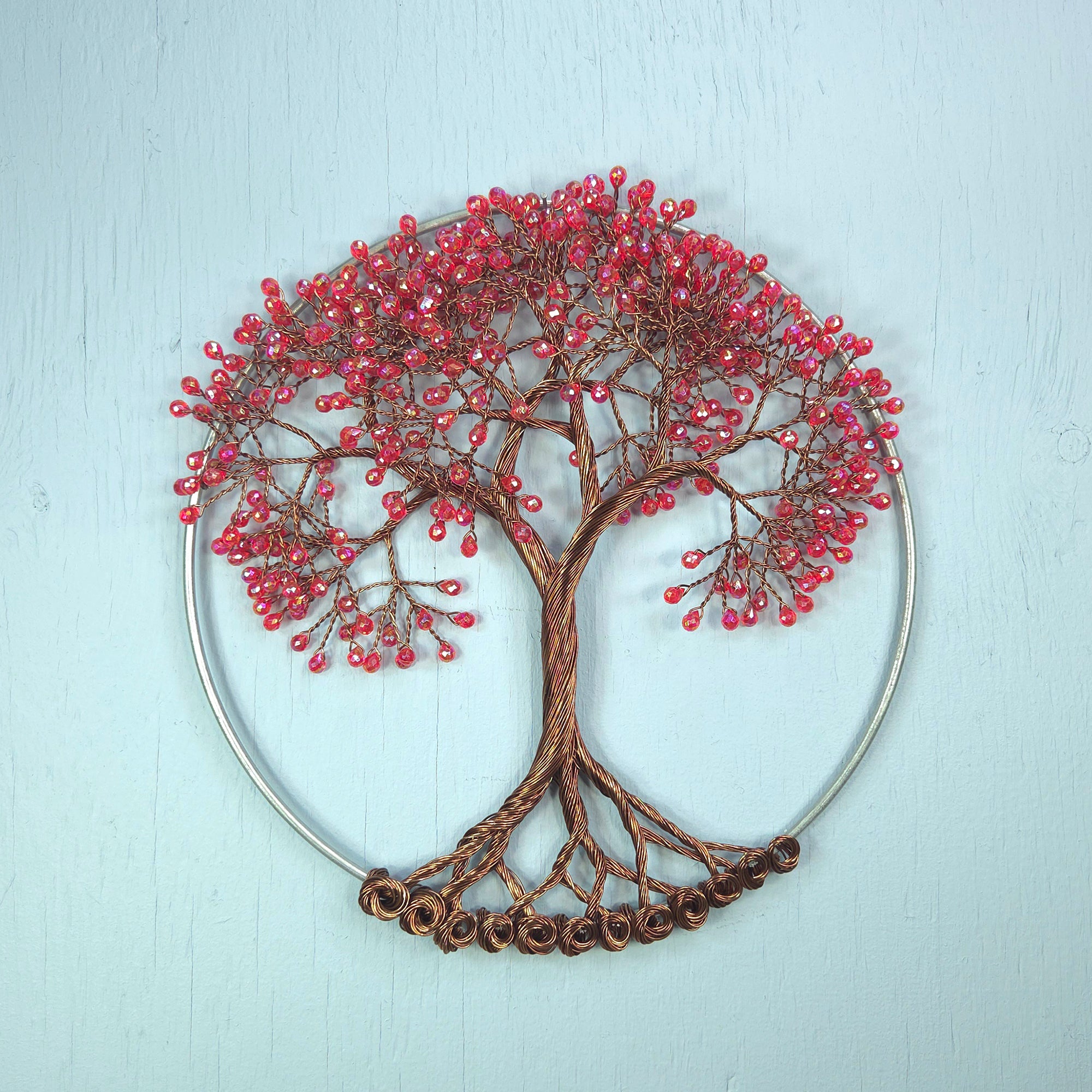 Decorative wall art of a tree with red berries on a light blue background