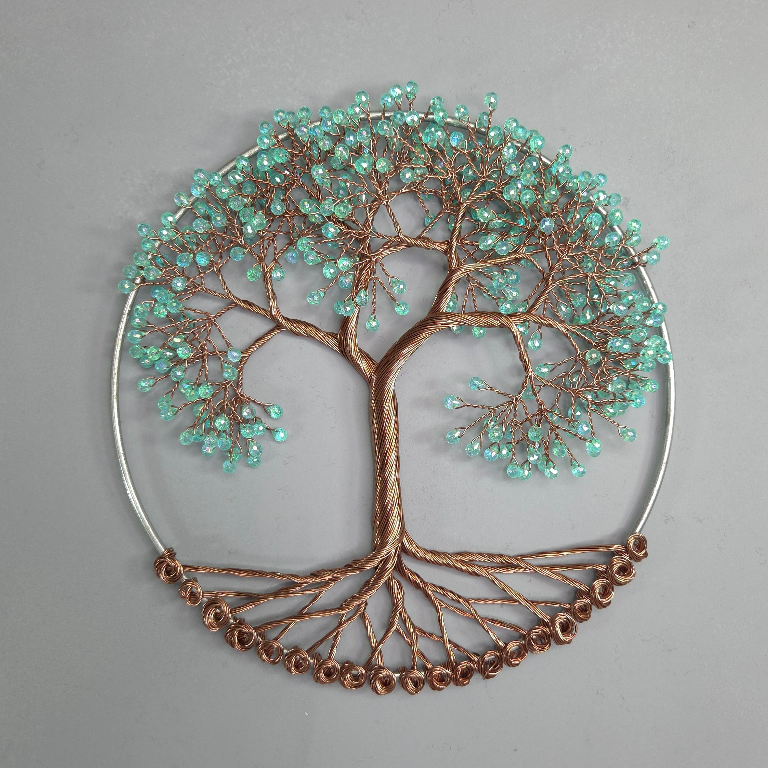Decorative wall art piece with tree design and turquoise beads on a gray background