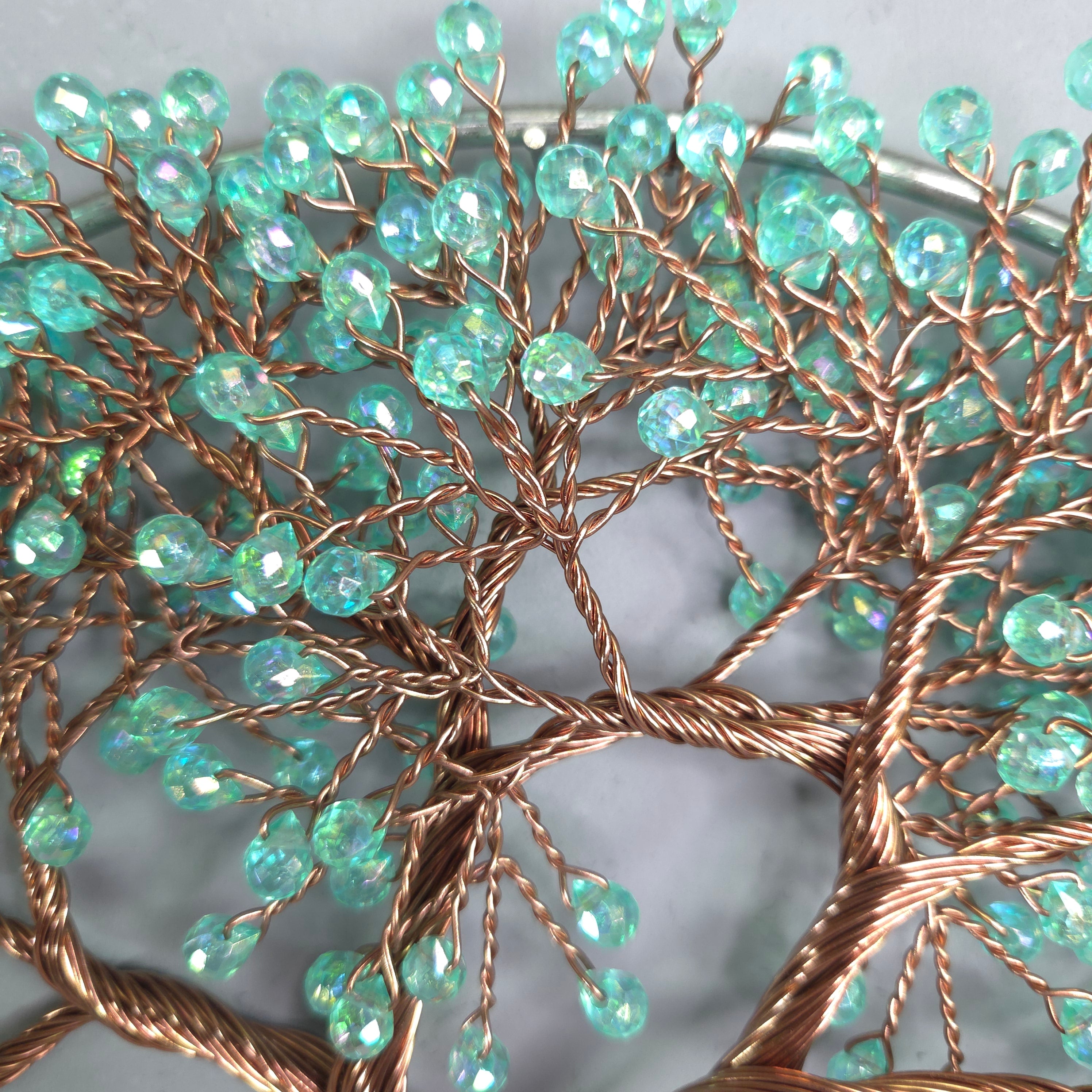 Decorative wall art with turquoise beads and copper wire on a light gray background
