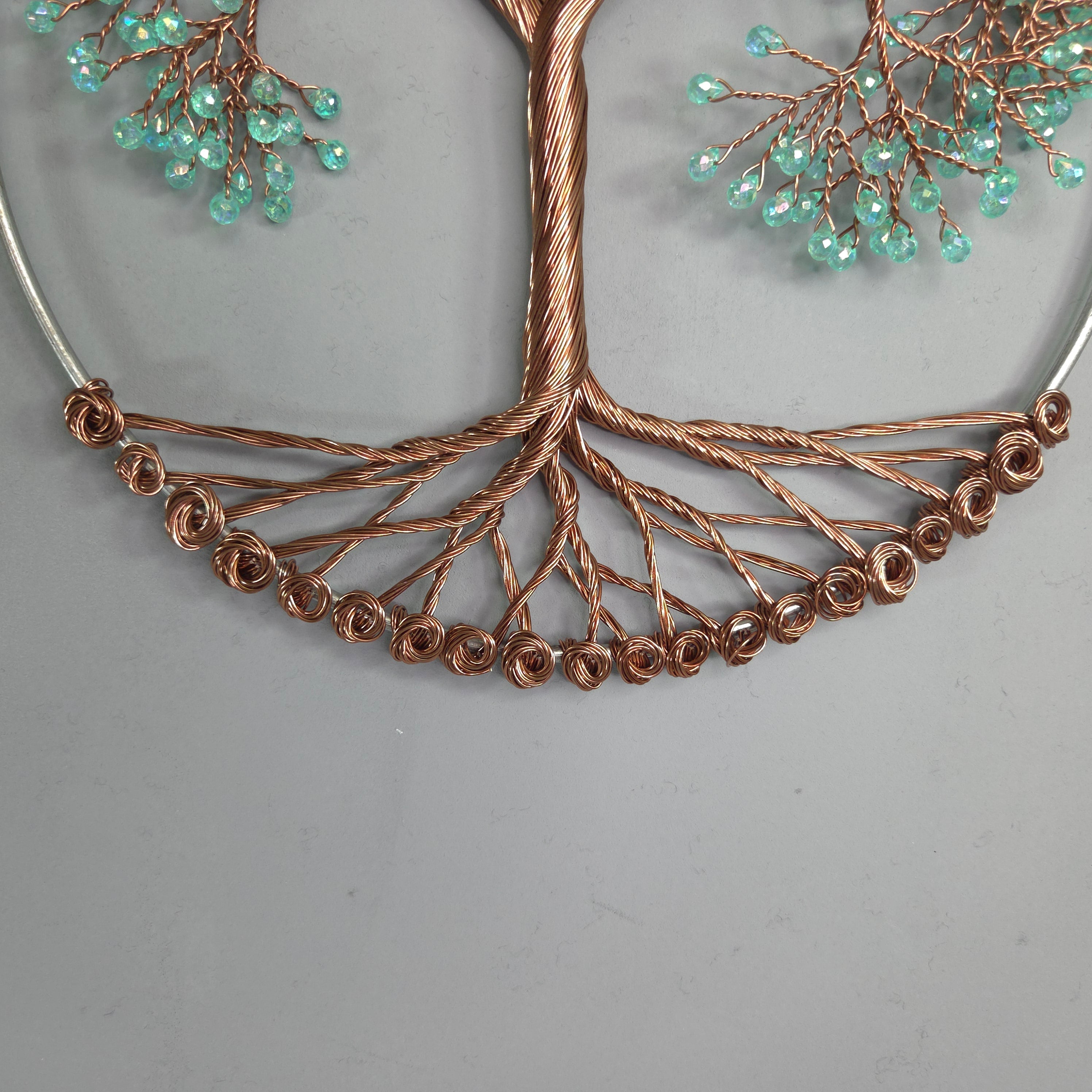 Decorative wall art of a tree with copper branches and green beads on a gray background