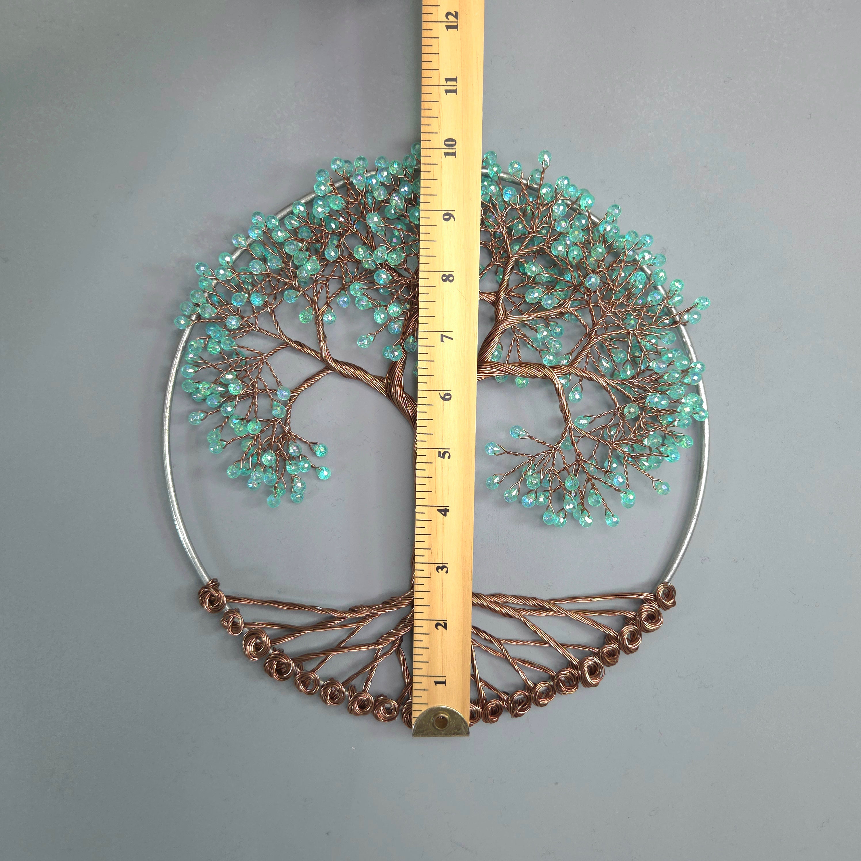 Decorative wall art with a tree design and a ruler for scale on a gray background