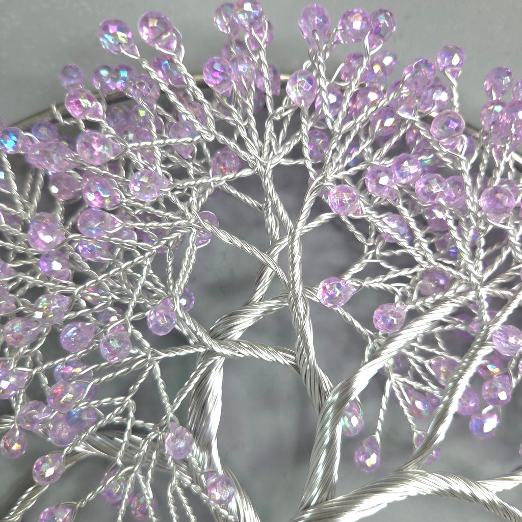 Decorative tree sculpture with purple beads on a gray background