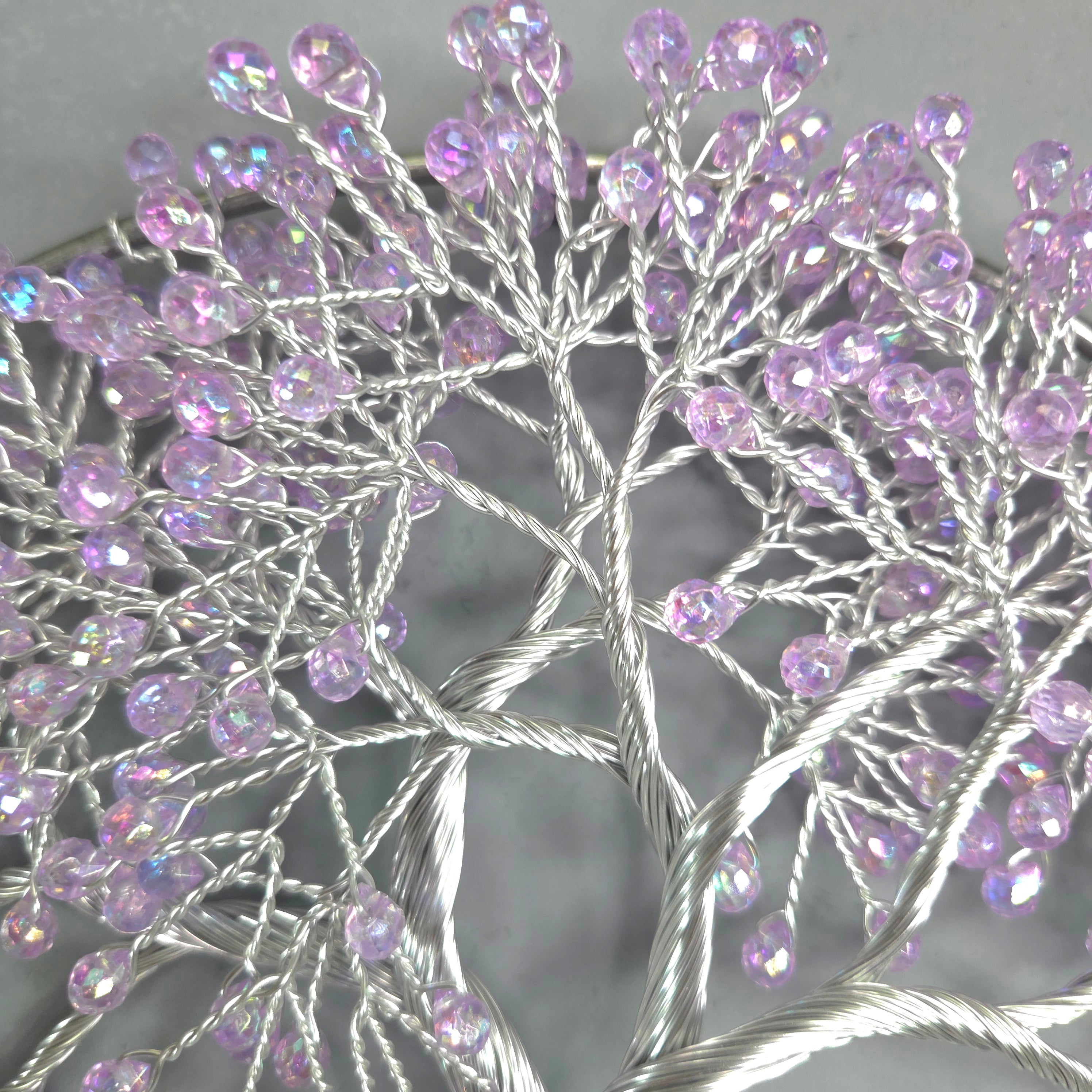 Decorative tree sculpture with purple beads on a gray background