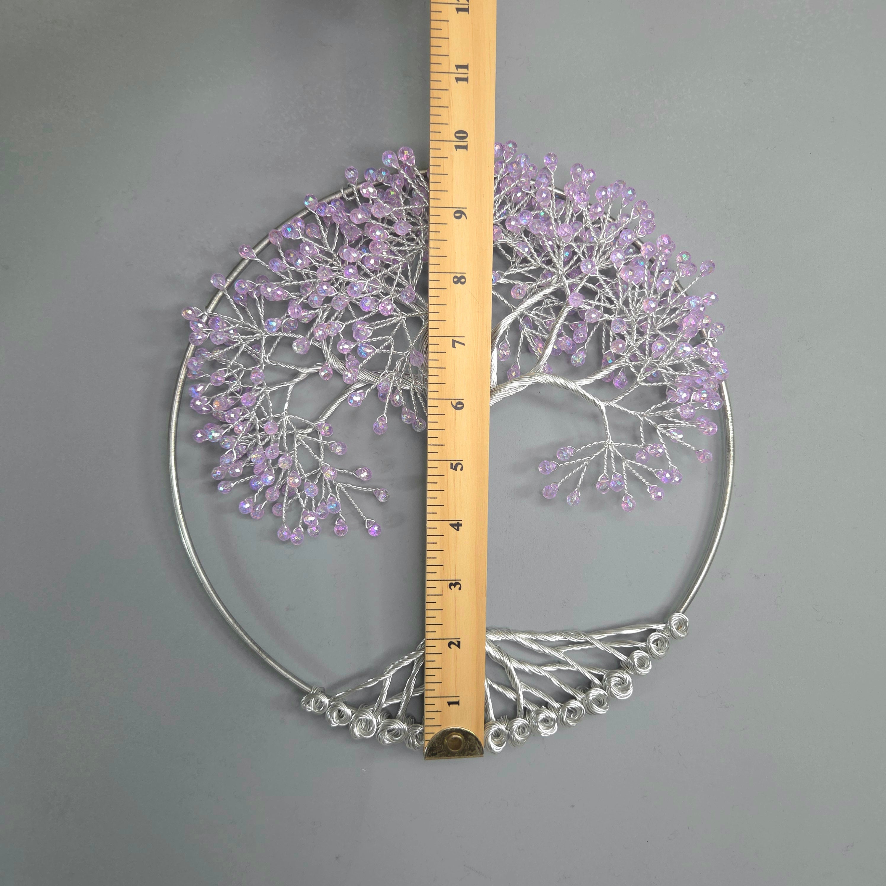 Decorative metal wall art with purple accents and a ruler for scale on a gray background