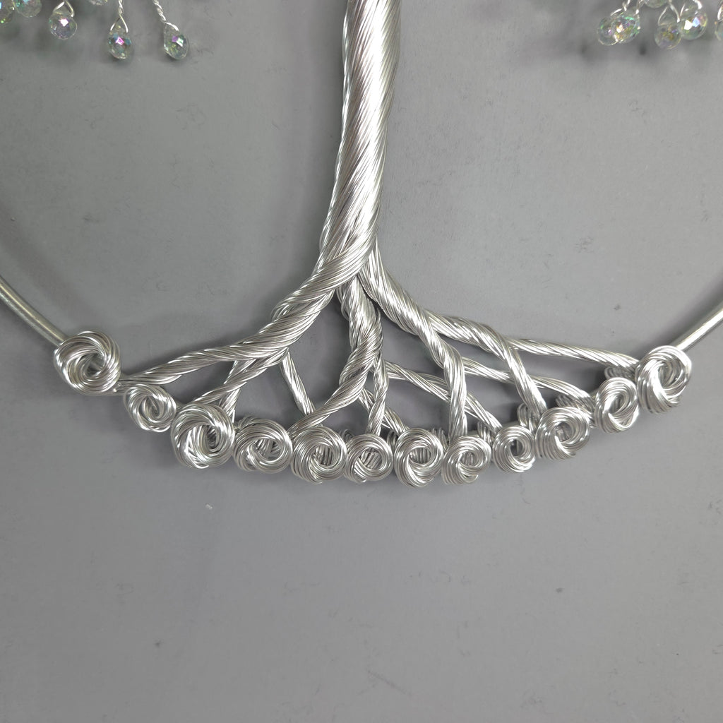 Silver tree-shaped jewelry piece on a gray background