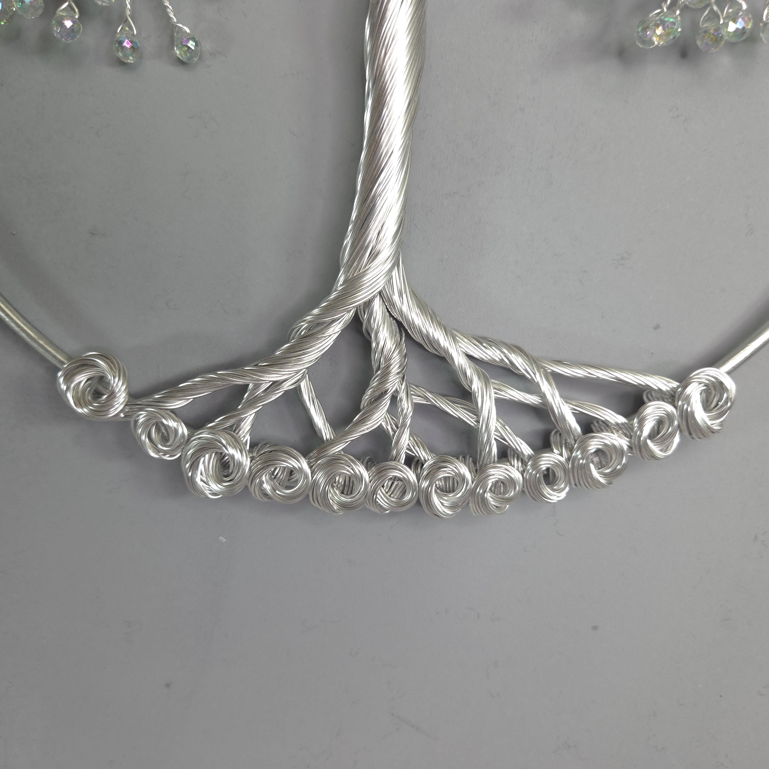 Silver tree-shaped jewelry piece on a gray background