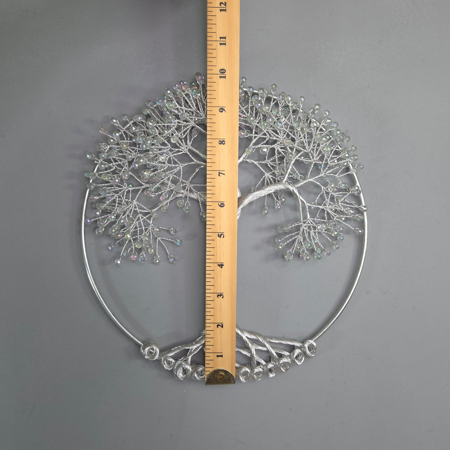 Decorative metal wall art with a ruler for scale on a gray background