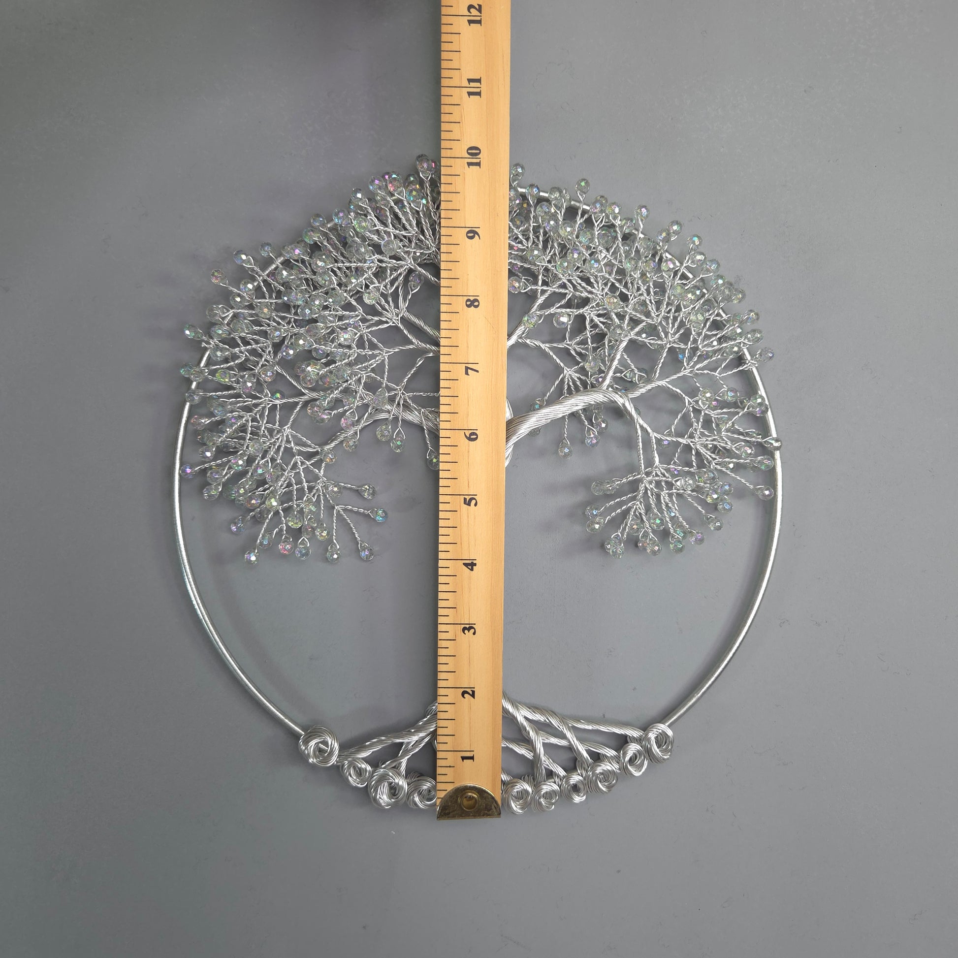Decorative metal wall art with a ruler for scale on a gray background
