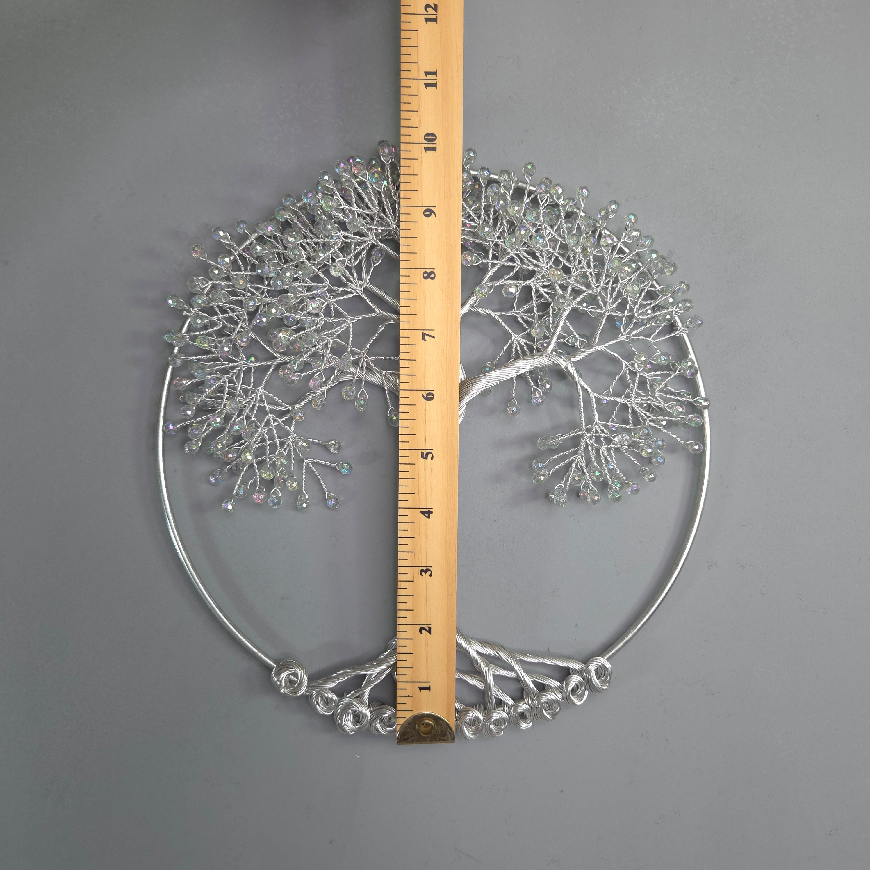 Decorative metal wall art with a ruler for scale on a gray background