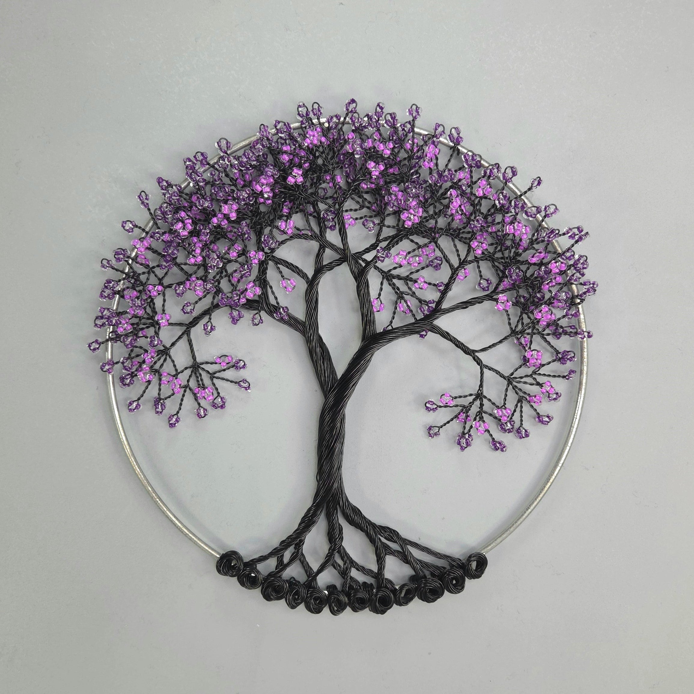 Decorative wall art of a tree with purple blossoms on a gray background