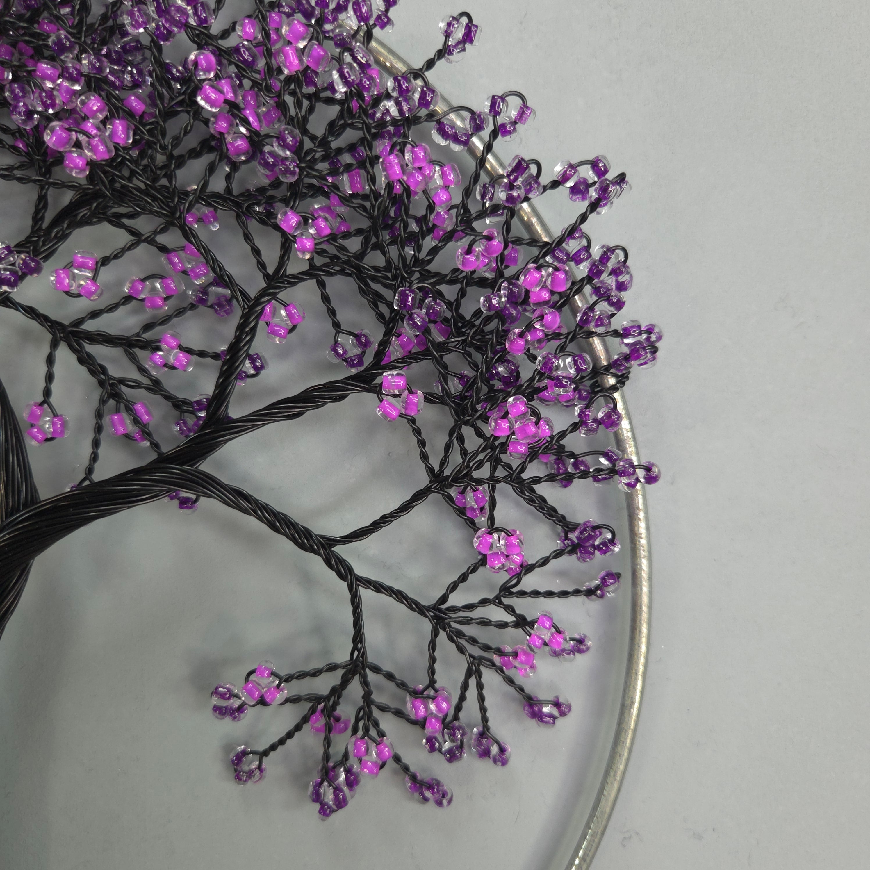 Decorative tree sculpture with purple beads on a gray background