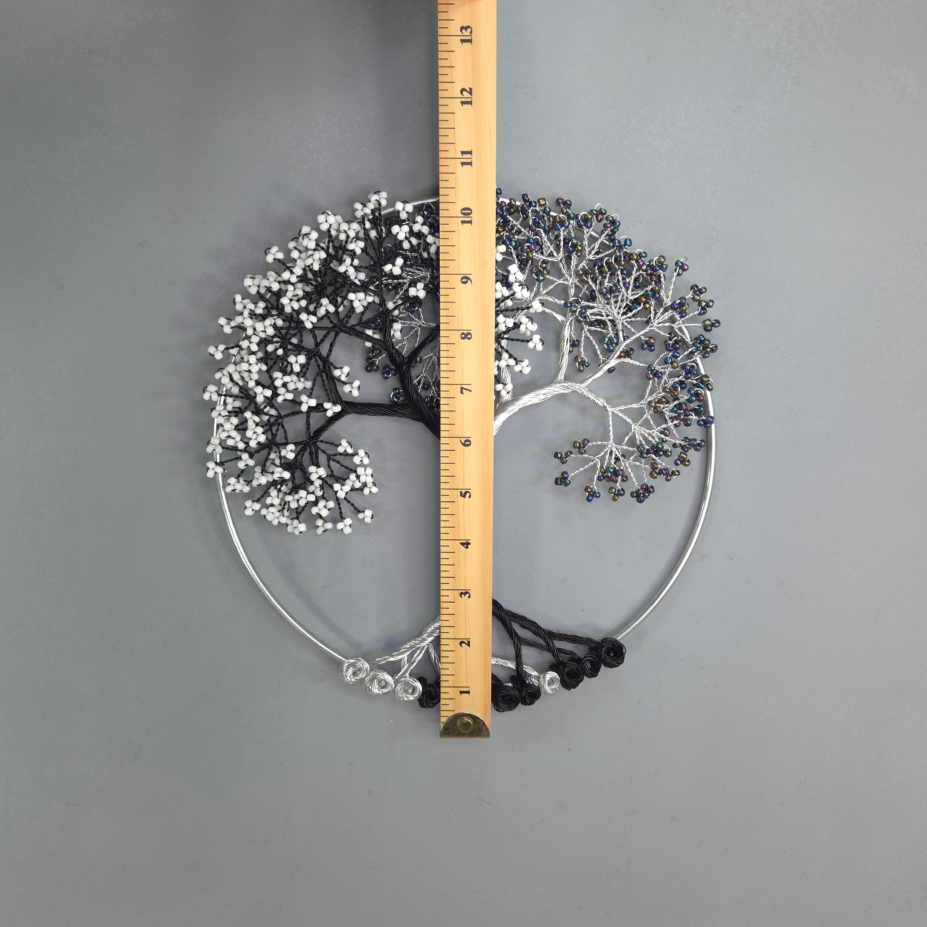 Decorative metal wall art with branches and leaves, measured against a ruler on a gray background