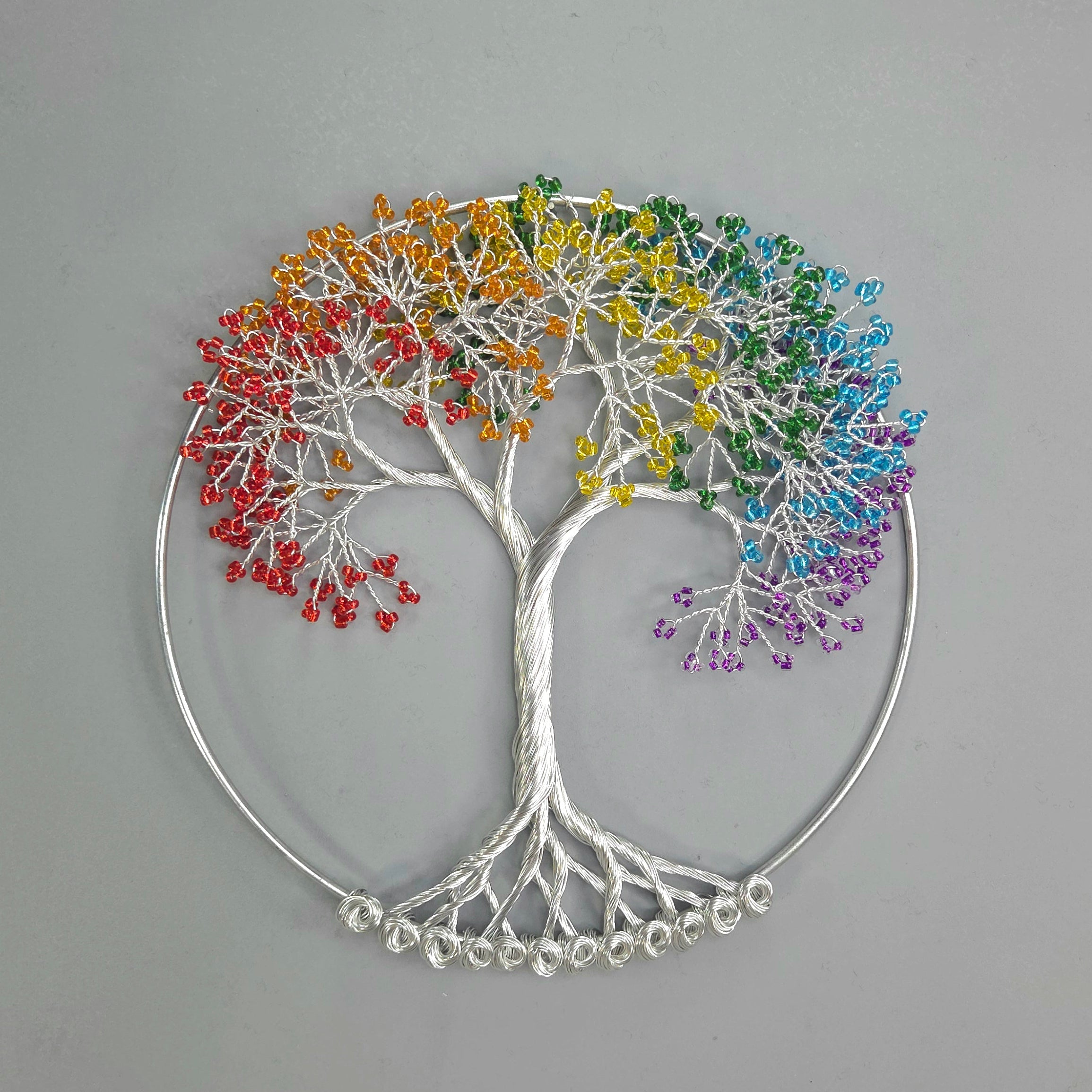 Decorative wall art of a tree with rainbow-colored leaves on a gray background