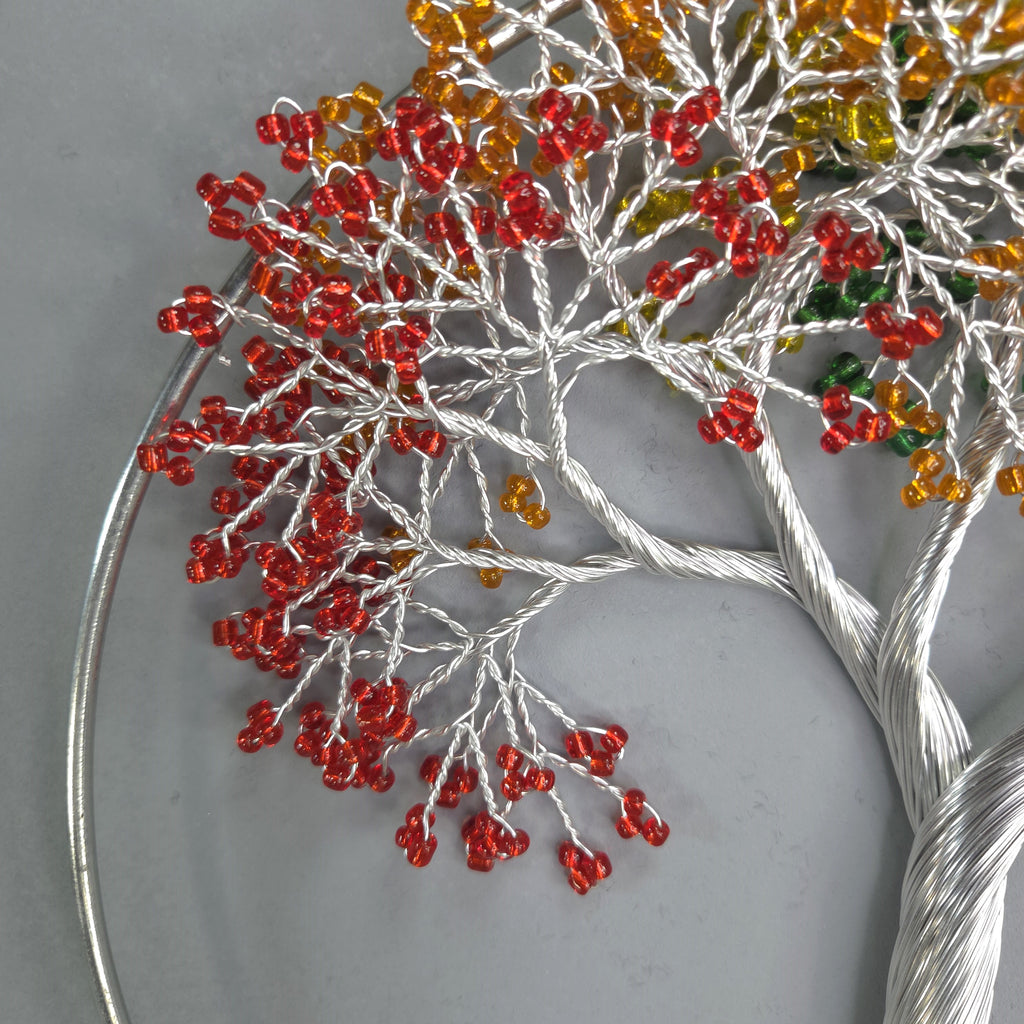 Decorative tree sculpture with red and orange beads on a gray background