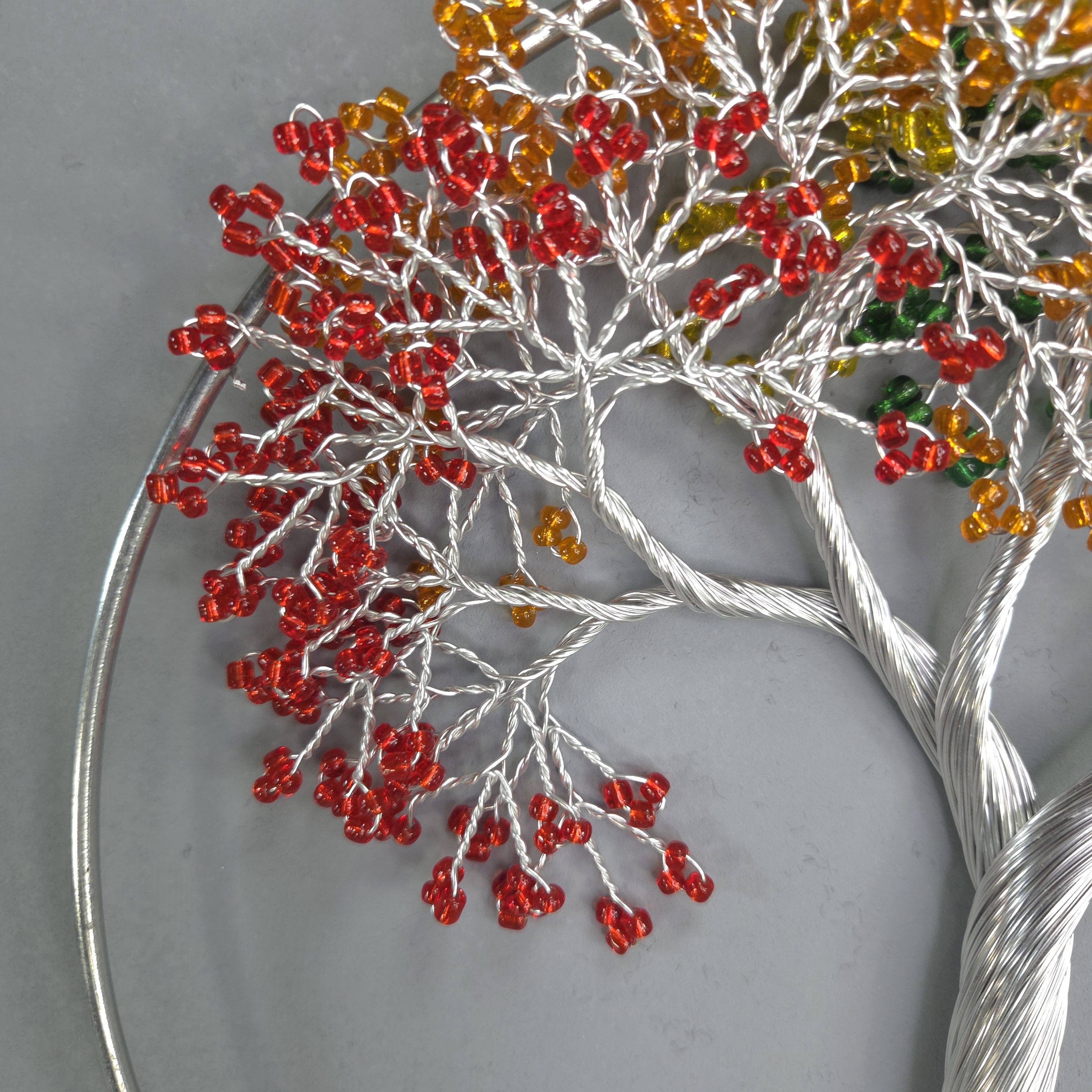 Decorative tree sculpture with red and orange beads on a gray background