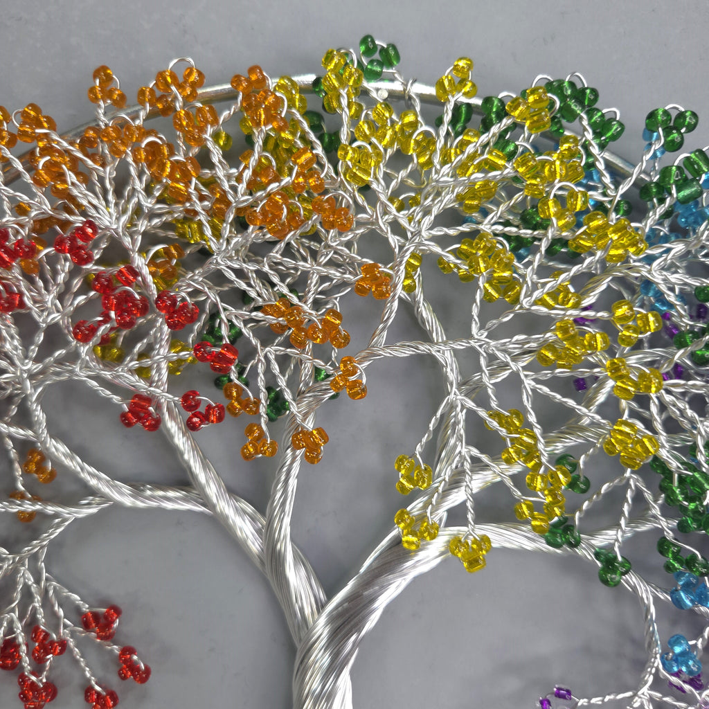 Decorative tree made of interwoven colorful beads on a gray background