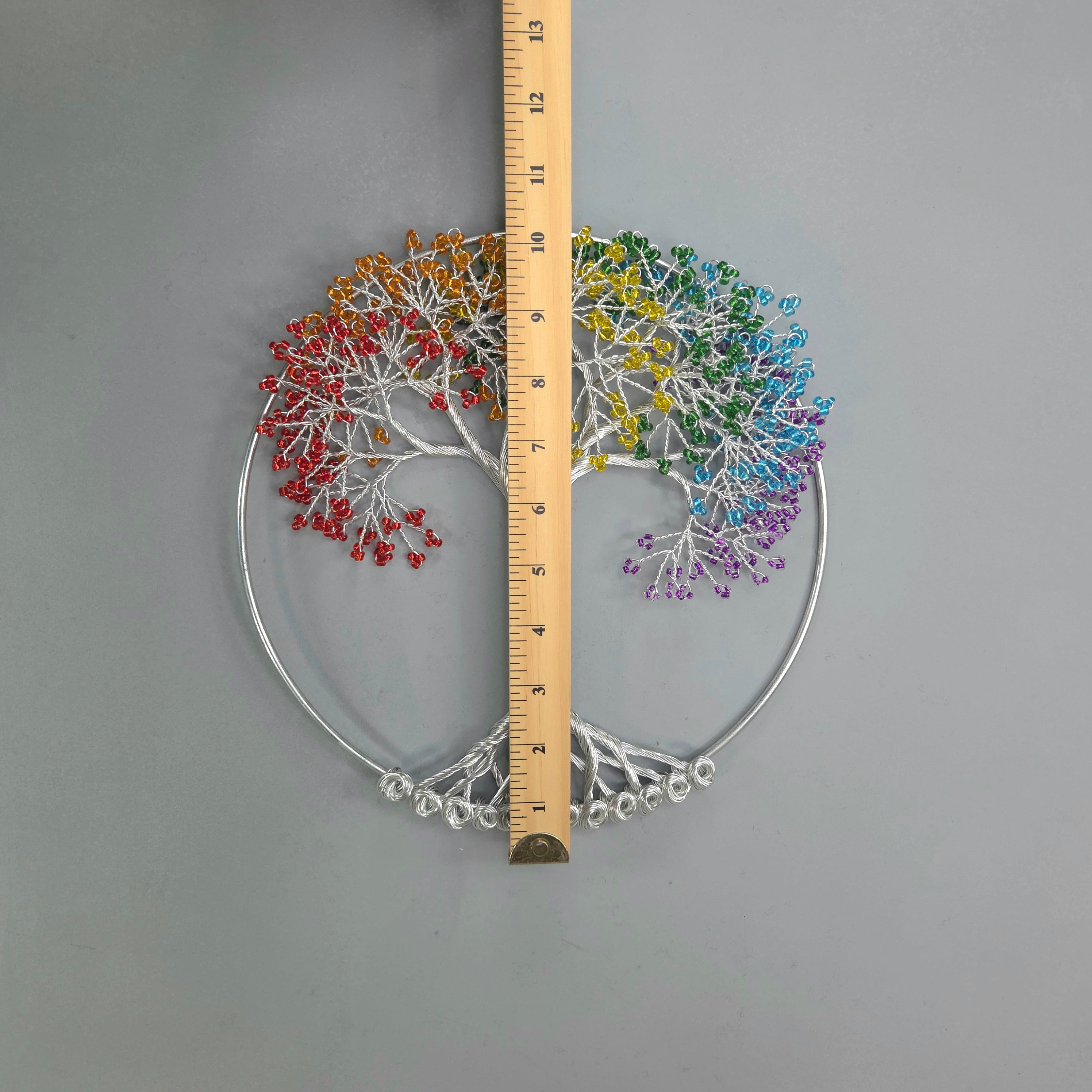 Colorful tree-shaped wall art with a ruler for scale on a gray background