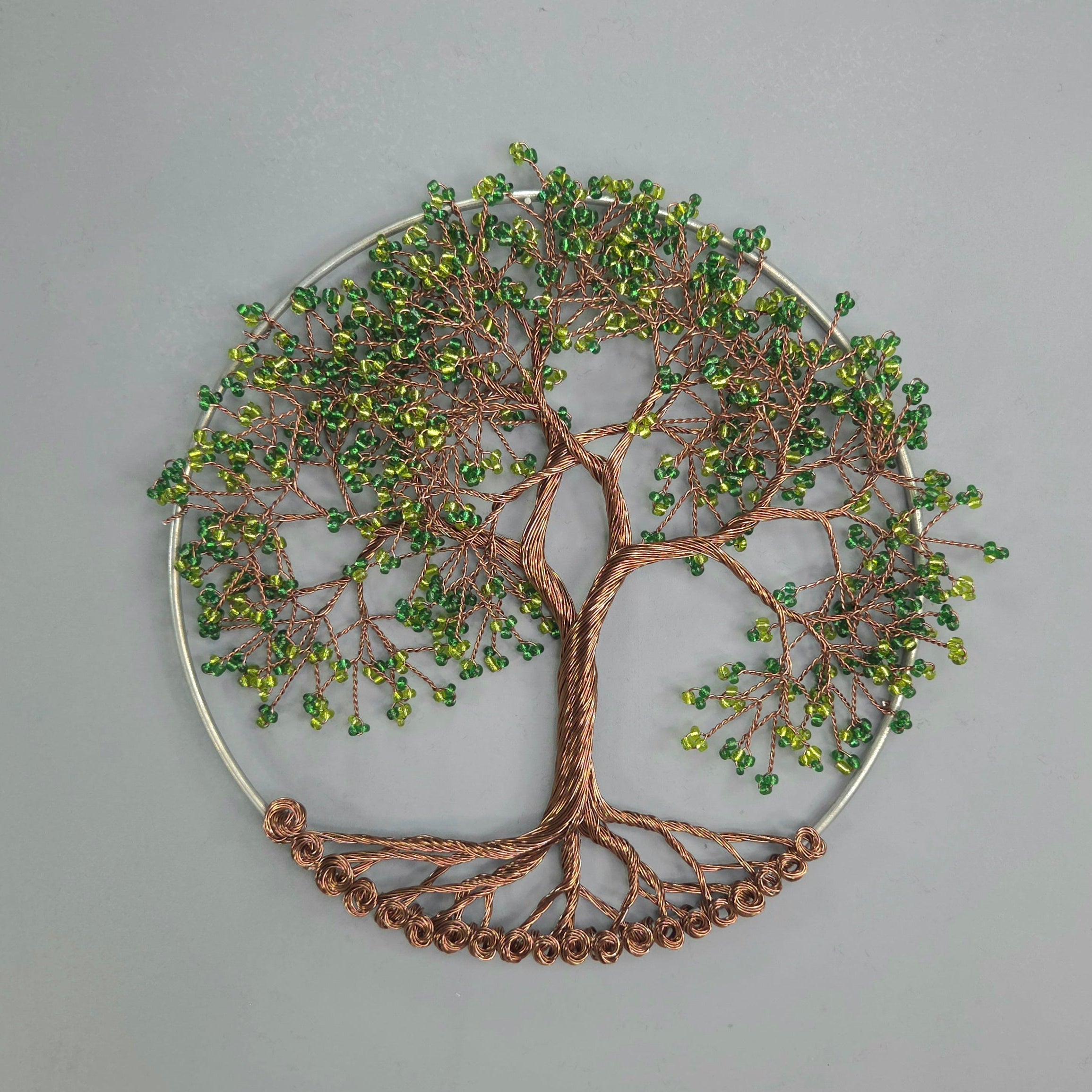 Decorative wall art of a tree with green beads on a gray background