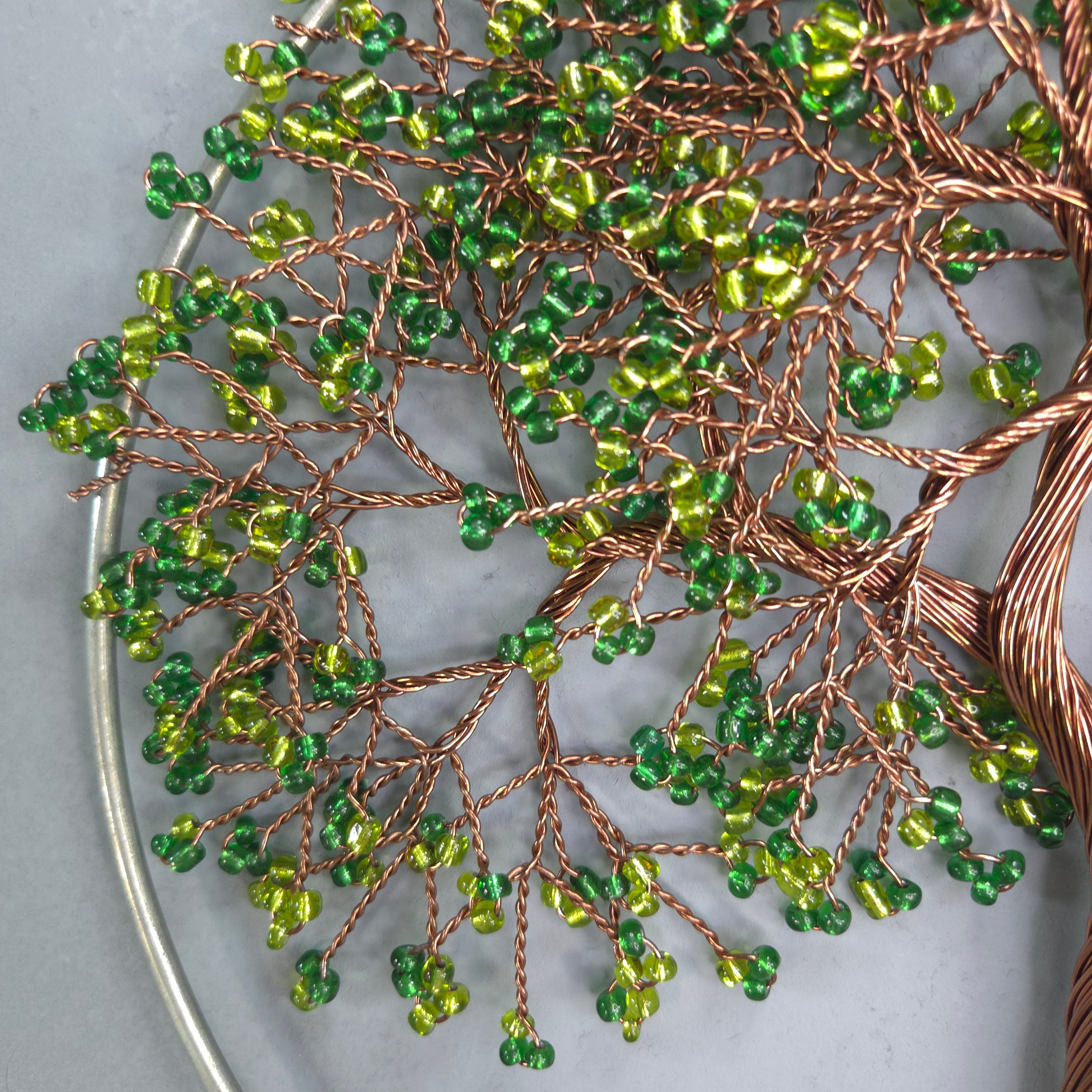 Decorative wreath with green beads and copper wire on a white surface